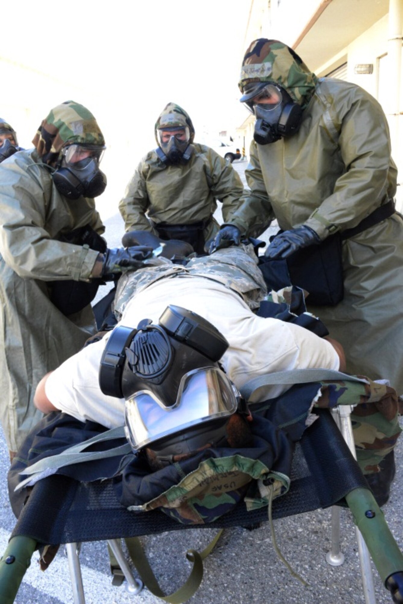 Staff Sgt. Jofred Aviles and Master Sgt. Russell Thomas, both from the 353rd Special Operations Support Squadron, prepare to use simulated 295 packets on Senior Airman Jeremiah Dobson, 353rd Special Operations Maintenance Squadron, as part of the decontamination process during an exercise held Jan. 29, 2014 on Kadena Air Base, Japan. The exercise is used to ensure SOG members are able to apply their skills needed to survive both chemical and conventional attacks. (U.S. Air Force photo/Tech. Sgt. Kristine Dreyer)