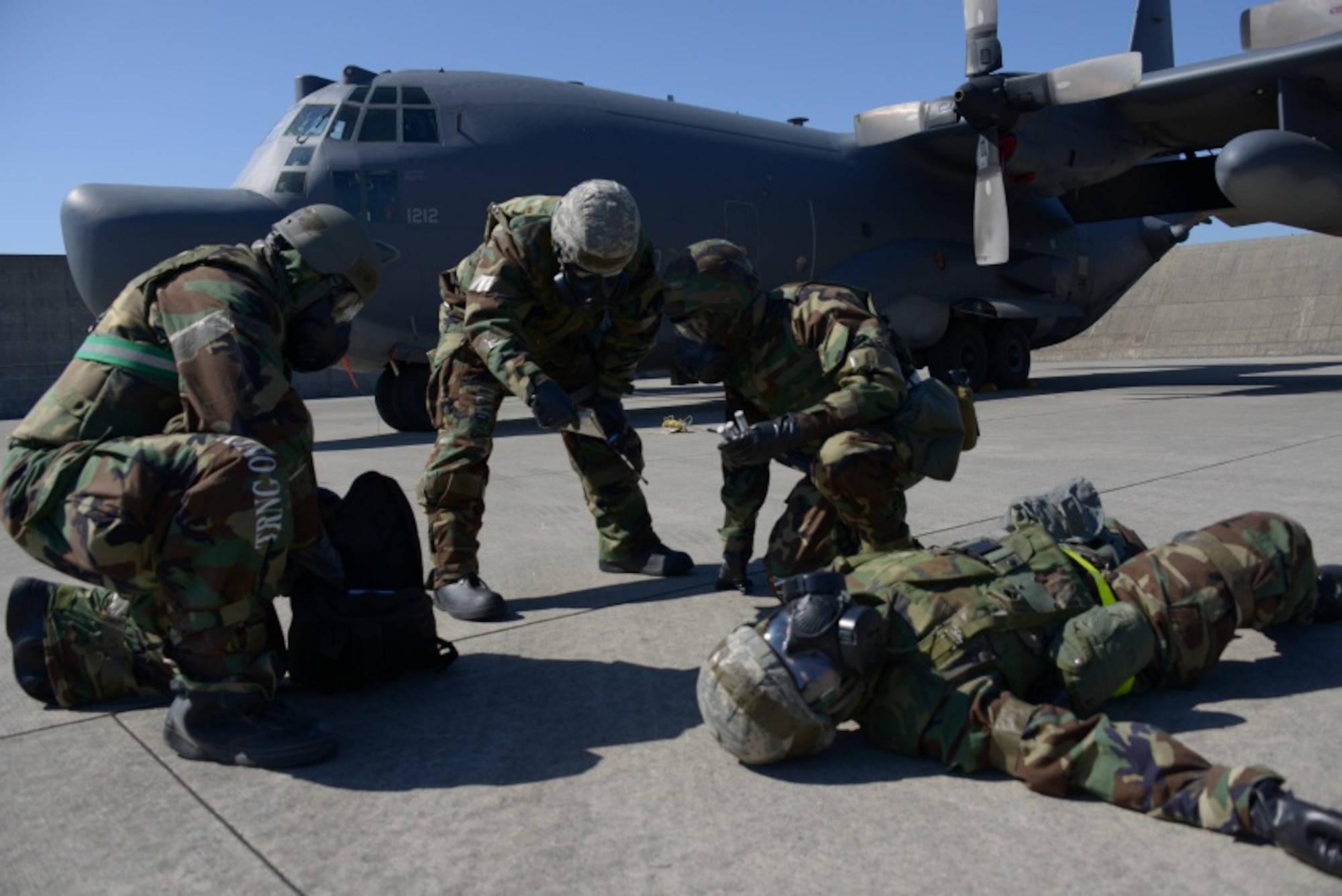 Staff Sgt. Joseph Johnson and Tech. Sgt. Jason Bretz, both from the 353rd Special Operations Maintenance Squadron, refer to the Airman’s Manual before administering nerve agent antidote injectors to Senior Airman Jeremiah Dobson, 353rd SOMXS, during an exercise Jan. 29, 2014 on Kadena Air Base.  During the exercise scenario, Dobson demonstrated nerve agent symptoms after a chemical attack.  The exercise is used to ensure SOG members are able to apply their skills needed to survive both chemical and conventional attacks. (U.S. Air Force photo/Tech. Sgt. Kristine Dreyer)