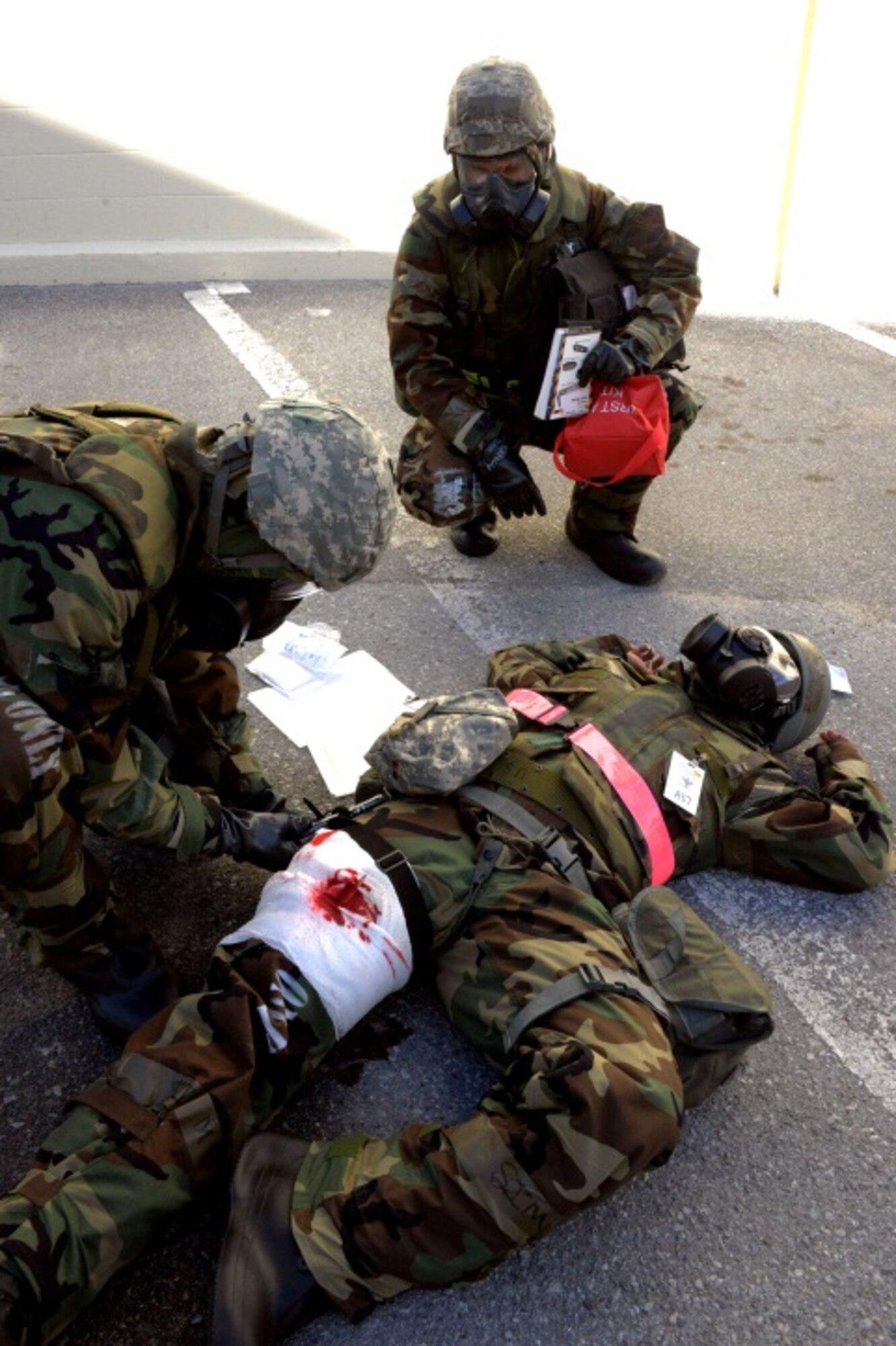 Senior Airman Phillip Togia, 353rd Special Operations Support Squadron, applies a tourniquet to Tech. Sgt. Ashunta Taylor, 353rd Special Operations Support Squadron, as Master Sgt. Jason Post, 353rd Special Operations Group, assists during an exercise Jan. 29, 2014 on Kadena Air Base.  Taylor is acting as a victim who was hit by shrapnel during a conventional attack.  The exercise is used to ensure SOG members are able to apply their skills needed to survive both chemical and conventional attacks.  (U.S. Air Force photo/Tech. Sgt. Kristine Dreyer)