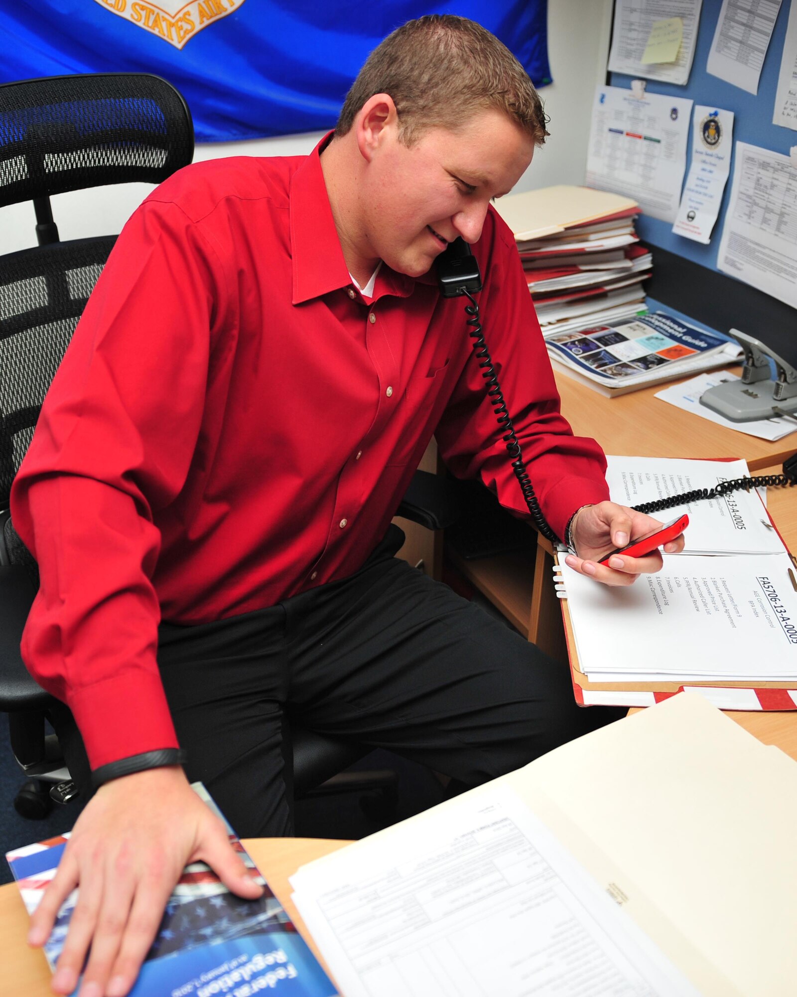 John Seacrist, a contacting specialist assigned to the 380th Expeditionary Contracting Squadron, speaks with service contractors over the phone here, Jan. 29, 2014. Seacrist oversees the services contracts on base. (U.S. Air Force photo by Staff Sgt. Michael Means/Released)
