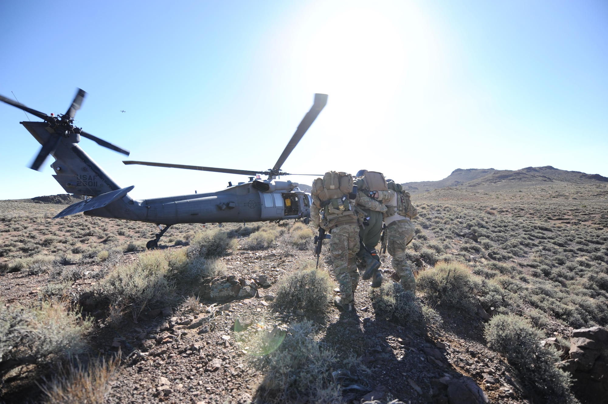Senior Airman Ronny Epps and Staff Sgt. Matthew Ritchie escort 1st Lt. Kyle Harrington to a waiting HH-60 Pave Hawk during a combat search and rescue scenario for exercise Red Flag 12-4, July 24, 2012, at the Nevada Test and Training Range. After nearly three hours of evading simulated enemy personnel, Harrington successfully made his way 1.8 miles to the extraction zone. Epps and Ritchie are pararescuemen from the 58th Rescue Squadron and Harrington is a B-1 bomber pilot with the 34th Bomb Squadron. (U.S. Air Force photo/Master Sgt. Sonny Cohrs) 
