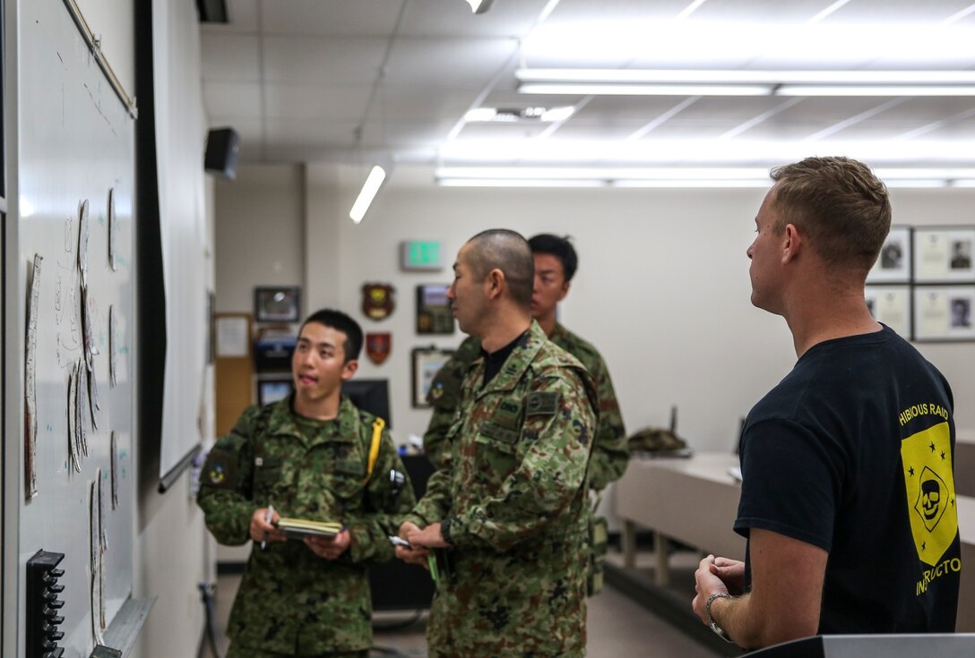 A soldier with the Japan Ground Self-Defense Force briefs a scheme of maneuver to amphibious raid instructors from the Expeditionary Warfare Training Group Pacific during Exercise Iron Fist 2014 aboard Naval Amphibious Base Coronado, Calif., Jan. 29, 2014. Iron Fist is an amphibious exercise that brings together Marines and sailors from the 15th Marine Expeditionary Unit, other I Marine Expeditionary Force units, and soldiers from the JGSDF, to promote military interoperability and hone individual and small-unit skills through challenging, complex and realistic training. (U.S. Marine Corps photo by Cpl. Emmanuel Ramos/Released) 