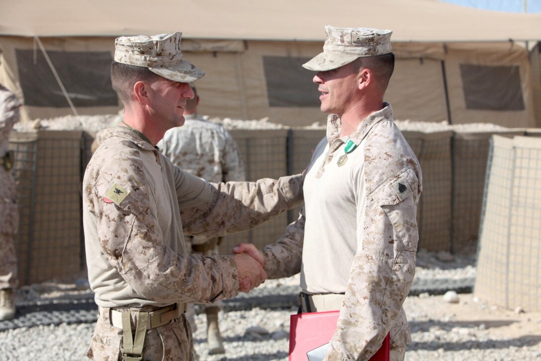 Col. Christopher Douglas, left, the team leader for Security Force Assistance Advisor Team 2-215, congratulates Sgt. Eddie Glowacki, a generator mechanic with SFAAT 2-215, on receiving the Navy and Marine Corps Commendation Medal aboard Forward Operating Base Nolay, Afghanistan Jan. 29, 2014. Glowacki, 33, a husband and a father of three, from Great Valley, N.Y., goes above and beyond his normal duties as a mechanic and helps with anything that needs to be done on FOB Nolay.
