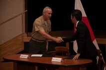 Mayor Tetsuji Matsumoto and Maj. Gen. Charles L. Hudson shake hands after signing a local implementation agreement Jan. 17 at Camp Kinser. The agreement specifies procedures for the evacuation of Okinawa residents in the event of a natural disaster, and the provisions for evacuation drills to maintain readiness. The agreement allows the residents of Urasoe City immediate and direct passage to higher ground or shelter via routes that pass through designated parts of the installation. The agreement helps maintain the strong relationship between the citizens and military personnel through their common goal to create a safer, more prepared community, according to Hudson. Matsumoto is the mayor of Urasoe City and Maj. Gen. Charles L. Hudson is the commanding general of Marine Corps Installations Pacific and Marine Corps Base Camp Smedley D. Butler.
