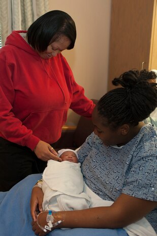 Téa Burke holds her newborn daughter, Noélani Burke, while Teisha Burke, her grandmother, touches her face at the Mike O'Callaghan Federal Medical Center Jan. 30, 2014, at Nellis Air Force Base, Nev. Noélani was delivered shortly after a disgruntled man brandishing a handgun outside the emergency room caused the hospital to be locked down. (U.S. Air Force photo by Airman 1st Class Timothy Young)