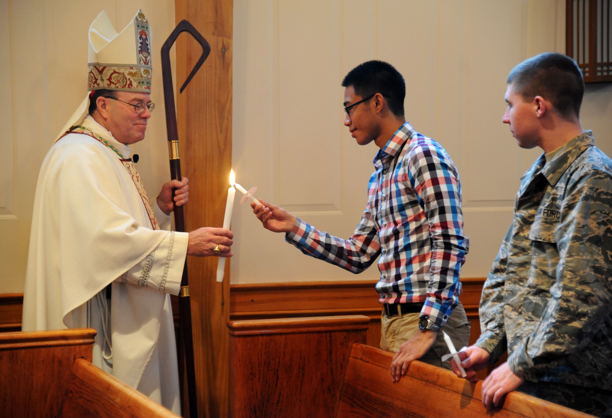 Bishop Neal Buckon, Archdiocese for Military Services, lights the candle of Airman 1st Class Kevin Mendoza at the beginning of Keesler’s Catholic Mass, led by Buckon, Feb. 2, 2014, at the Triangle Chapel, Keesler Air Force Base, Miss.  Buckon also met with technical training students for prayer and dinner Jan. 31, during his visit to Keesler.  (U.S. Air Force photo by Kemberly Groue)