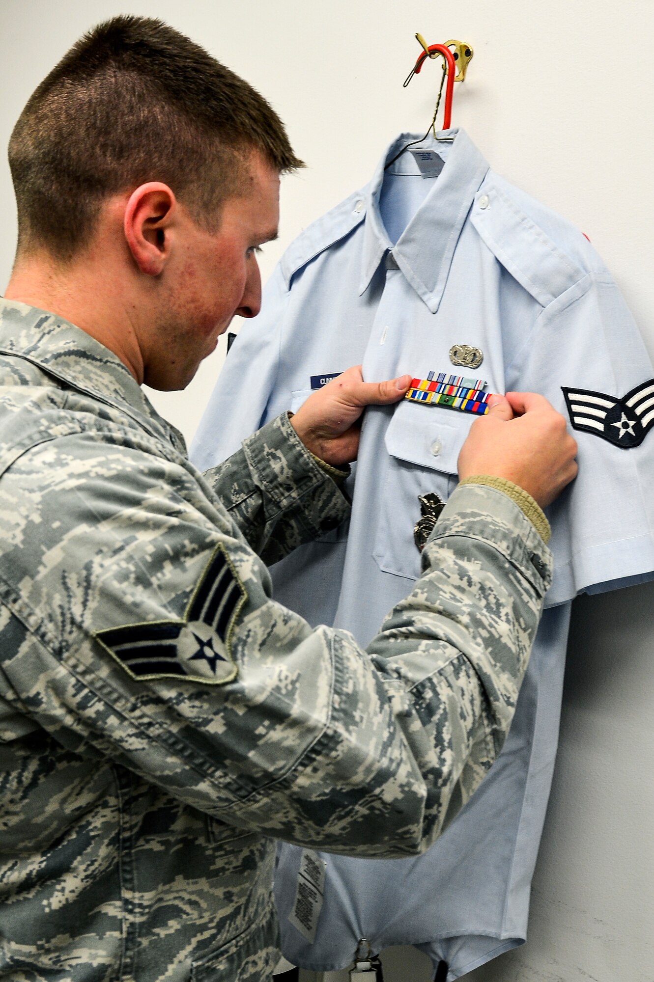 Senior Airman Joshua Cunningham, 460th Mission Support Group Airman category annual award nominee, prepares his uniform before taking an official photograph as part of his annual award package Feb. 3, 2014, at the 460th Space Wing Public Affairs Office on Buckley Air Force Base, Colo. The photograph was one requirement for the annual awards competition, which also included meeting a board of four Buckley chief master sergeants. (U.S. Air Force photo by Senior Airman Riley Johnson/Released)