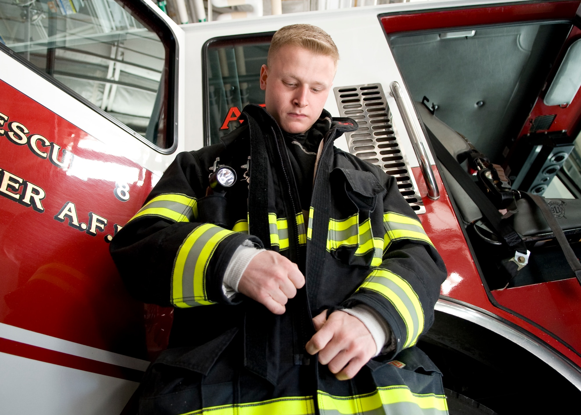 Airman 1st Class Logan Brouse, 436th Civil Engineer Squadron firefighter, zips up his bunker coat Jan. 30, 2014, at the fire department on Dover Air Force Base, Del. Brouse is following in his father’s footsteps by becoming an Air Force firefighter. (U.S. Air Force photo/Airman 1st Class Zachary Cacicia)