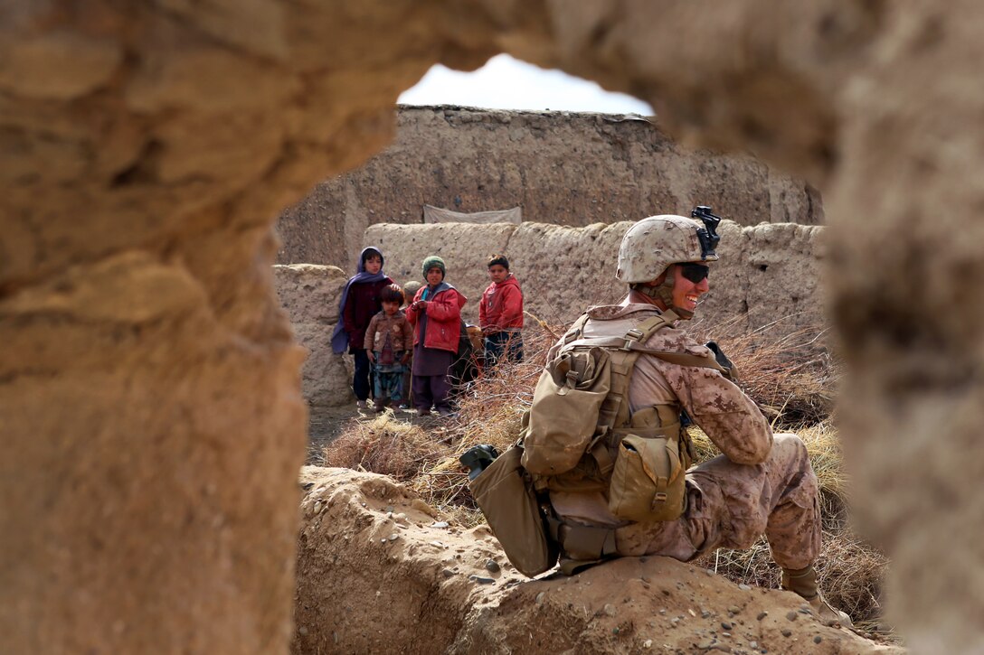 Afghan children watch as U.S. Marines conduct a joint patrol with Afghan local police outside Camp Dwyer in Helmand province, Afghanistan, Jan. 21, 2014.