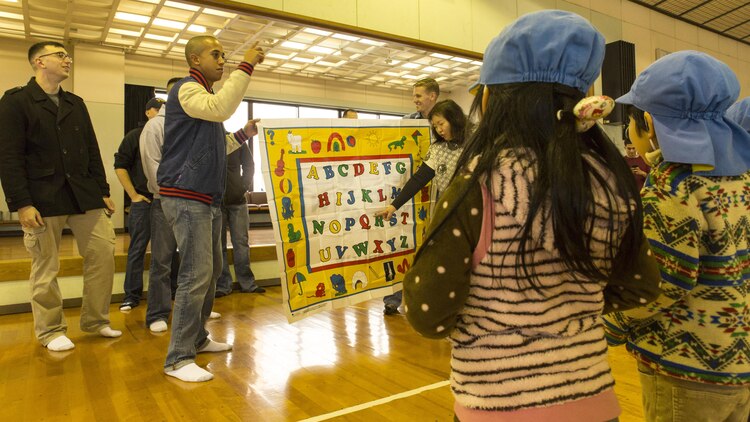 Service members aboard Marine Corps Air Station Iwakuni, Japan, teach the English alphabet to students from Ekimae Hoikuen Pre-School, Jan. 28, 2014, in a community relation visit hosted by the Marine Memorial Chapel. Students recited the alphabet, then service members recited and finally, both parties sang the alphabet song in harmony. Service members came to the pre-school to teach basic English skills to students and strengthen the Japanese-American relationship.