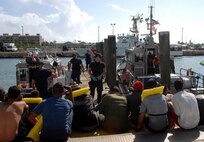 A Coast Guardsman watches over the 26 Cuban immigrants his crew just unloaded from a 44-foot Special Purpose Craft-Law Enforcement boat Feb. 3, 2014, at U.S. Coast Guard Sector Key West. The crew of the 44-foot boat, along with the 33-foot boat that also picked up the immigrants docked just as North American Aerospace Defense Command and U.S. Northern Command Senior Enlisted Leader, Robert Winzenried, Chief Master Sgt. Joseph Sluder, Joint Task Force-North Command Chief, and Chief Master Sgt. Ron Anderson, Air Forces North Command Chief, were touring the facility. Prior to the tour, the senior enlisted leaders spoke to leadership about the command's mission and the support they receive from their respective agencies. Photo by Air Force Master Sgt. Chuck Marsh/Released.