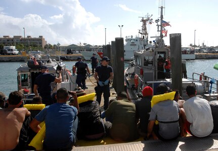 A Coast Guardsman watches over the 26 Cuban immigrants his crew just unloaded from a 44-foot Special Purpose Craft-Law Enforcement boat Feb. 3, 2014, at U.S. Coast Guard Sector Key West. The crew of the 44-foot boat, along with the 33-foot boat that also picked up the immigrants docked just as North American Aerospace Defense Command and U.S. Northern Command Senior Enlisted Leader, Robert Winzenried, Chief Master Sgt. Joseph Sluder, Joint Task Force-North Command Chief, and Chief Master Sgt. Ron Anderson, Air Forces North Command Chief, were touring the facility. Prior to the tour, the senior enlisted leaders spoke to leadership about the command's mission and the support they receive from their respective agencies. Photo by Air Force Master Sgt. Chuck Marsh/Released.