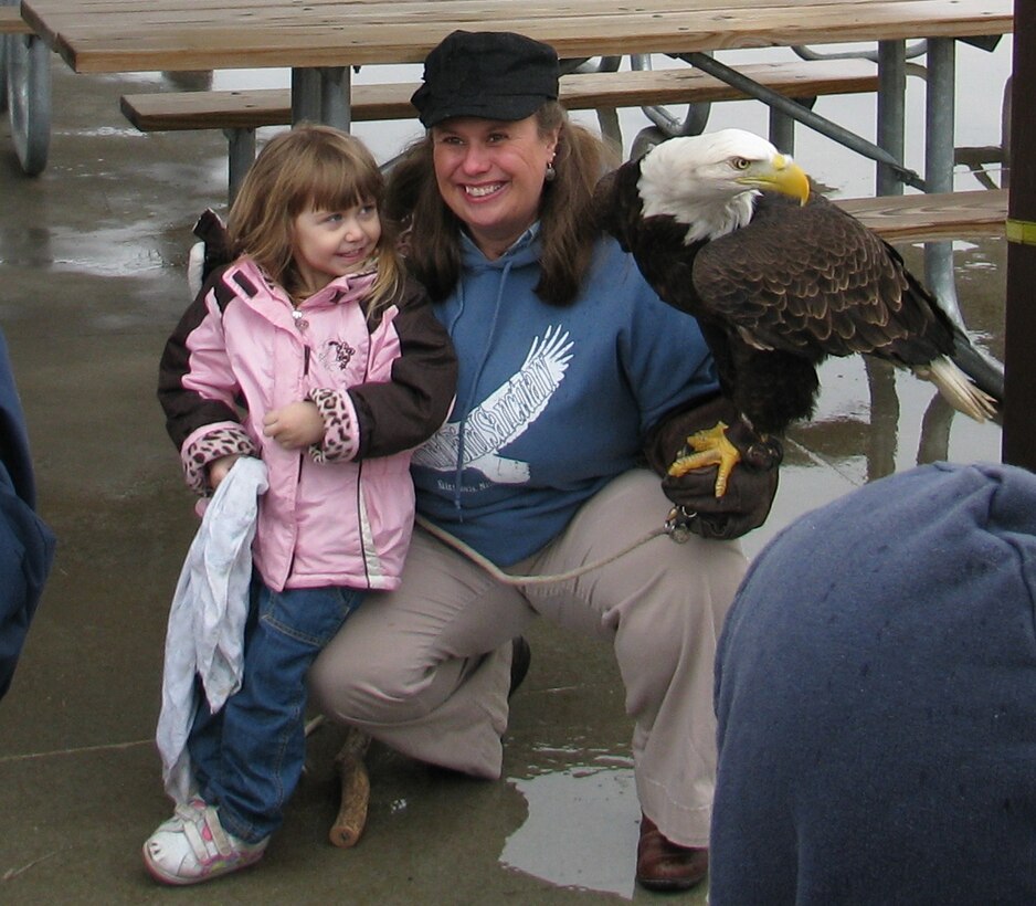 Cathy Spahn, educator from the World Bird Sanctuary in Valley Park, Mo., and Patriot, a rehabilitated bald eagle pose for pictures with visitors at the 4th Annual Kaskaskia Eagle Fest Feb. 1, 2014.