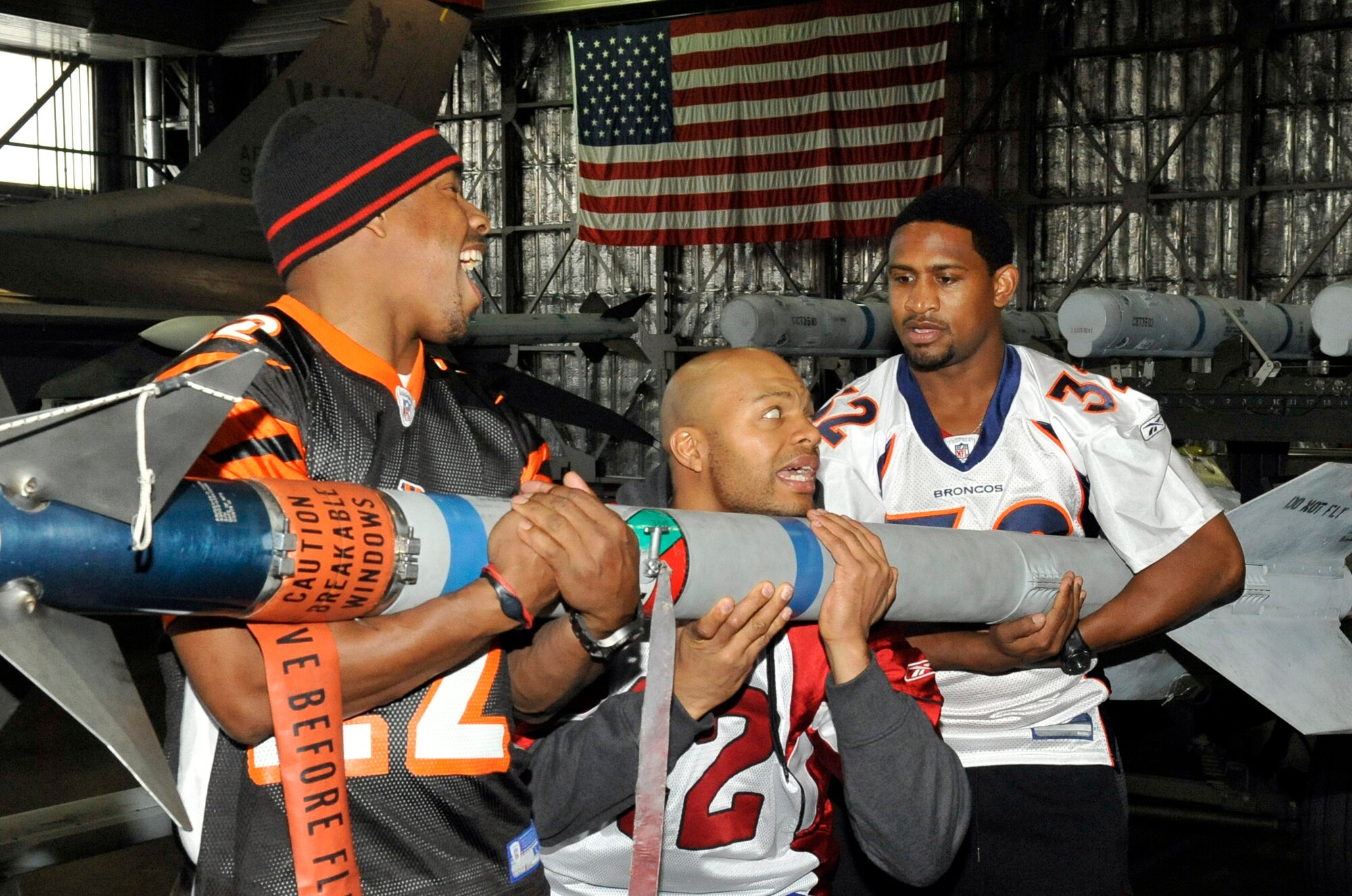 Nate Clements, left, Terrence Holt, middle, and Dre Bly, National Football League alumni, attempt to pick up an AIM-9 sidewinder at Misawa Air Base, Japan, Jan. 31, 2014. This missile is commonly lifted by a similar three-man team in a weapons load crew competition. (U.S. Air Force photo by Airman 1st Class Zachary Kee) 
