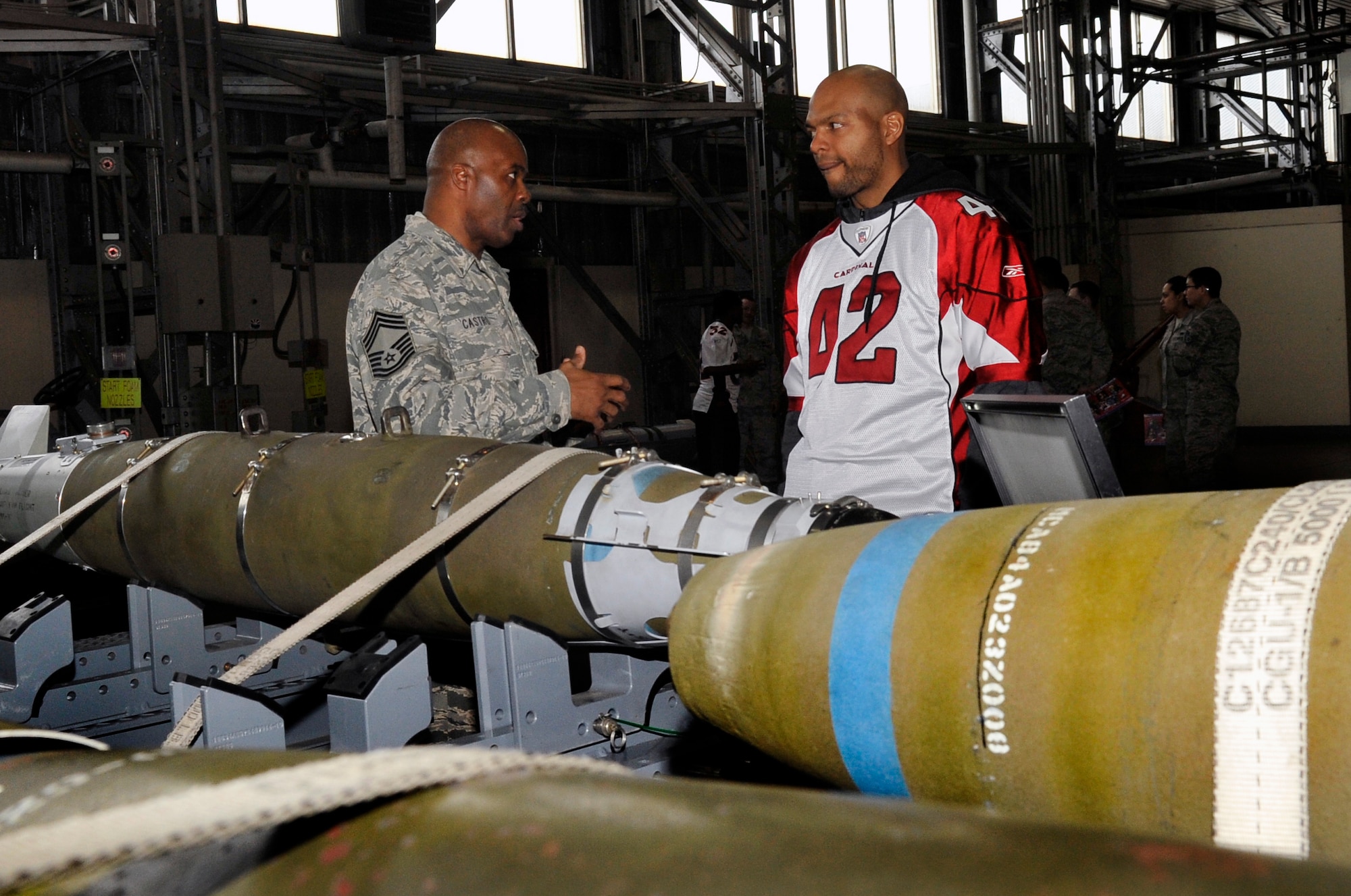 Chief Master Sgt. Kim Castro Sr., 35th Maintenance Group wing weapons manager, shows a guided bomb unit-54 to Terrence Holt, National Football League alumnus, at Misawa Air Base, Japan, Jan. 31, 2014. Holt and his fellow alumni were able to capture a glimpse of what goes on at Misawa while seeing different static displays. (U.S. Air Force photo by Airman 1st Class Zachary Kee)