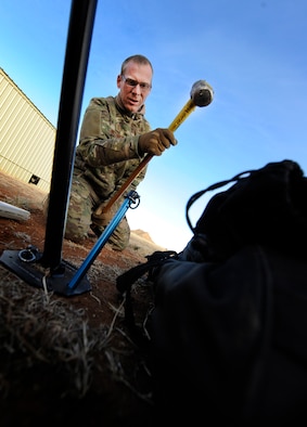 Senior Master Sgt. Timothy Pettigrew, 1st Special Operations Communications Squadron operations chief, hammers a spike into the ground at Cannon Air Force Base, N.M., Jan. 24, 2014. Pettigrew set up ground to air communications equipment in support of an emergency deployment readiness exercise. (U.S. Air Force photo/Staff Sgt. Jeff Andrejcik)
