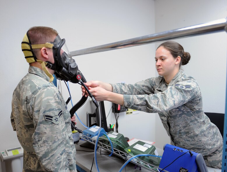 U.S. Air Force Airman 1st Class Brian Harvey, left, 7th Aerospace Medical Squadron, is fitted with a gas mask by Airman 1st Class Leah Smith, 7th Aerospace Medical Squadron, Feb. 3, 2014,  at Dyess Air Force Base, Texas. The bioenvironmental flight technicians must ensure that there are no leaks and each mask is properly fit. (U.S. Air Force photo by Airman 1st Class Kedesha Pennant/Released)