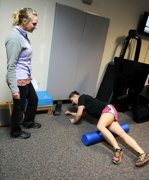 Alyssa Lamsina, left, 7th Medical Operations Squadron physical therapist assistant, looks on as 2nd Lt. Cassandra Hill, 7th Logistics Readiness Squadron, performs foam rolling along techniques Jan. 24, 2014, at Dyess Air Force Base, Texas. Patients can make an appointment at the Dyess physical therapy clinic without having to see their primary care manager. (U.S. Air Force photo by Airman 1st Class Kedesha Pennant/Released)