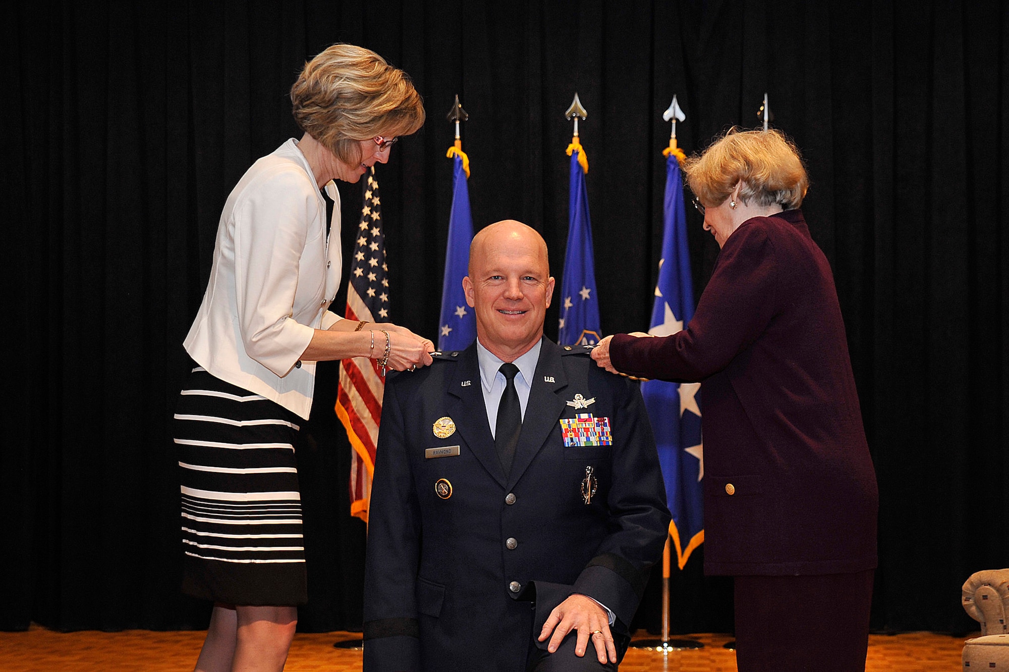 VANDENBERG AIR FORCE BASE, Calif. – Lt. Gen. John W. “Jay” Raymond, Joint Functional Component Command for Space and 14th Air Force commander, kneels as his wife, Mollie (left), and his mother, Barbara Raymond, pin on his third star during his promotion ceremony Jan. 31, 2014. The ceremony was held at the Pacific Coast Club here where he was promoted from major general to lieutenant general prior to accepting command of JFCC Space and 14th AF. (U.S. Air Force photo/Michael Peterson) 