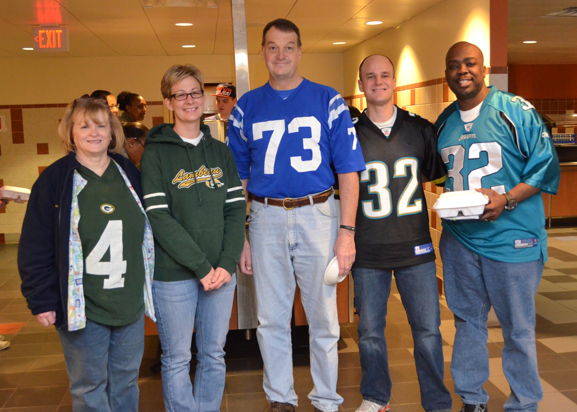 Brig. Gen. (Dr.) Kory Cornum, Keesler Medical Center commander, center, stands with several medical center “Dragon Medics” in the facility’s Hungry Dragon dining facility Jan. 24, during “Jersey Day” at Keesler Air Force Base.  He is sporting the jersey he wore as a U.S. Air Force Academy Falcons defensive end 34 years ago.  Cornum has been selected to become the Air Mobility Command command surgeon after serving in his current post for four year.  Showing their colors are, from left, Susan Givens,	2st Lt. Cristi Dueker-Bray and Senior Airman Daniel Worsham, 81st Medical Operations Squadron, and Master Sgt. Gene McCants, 81st Medical Group.
