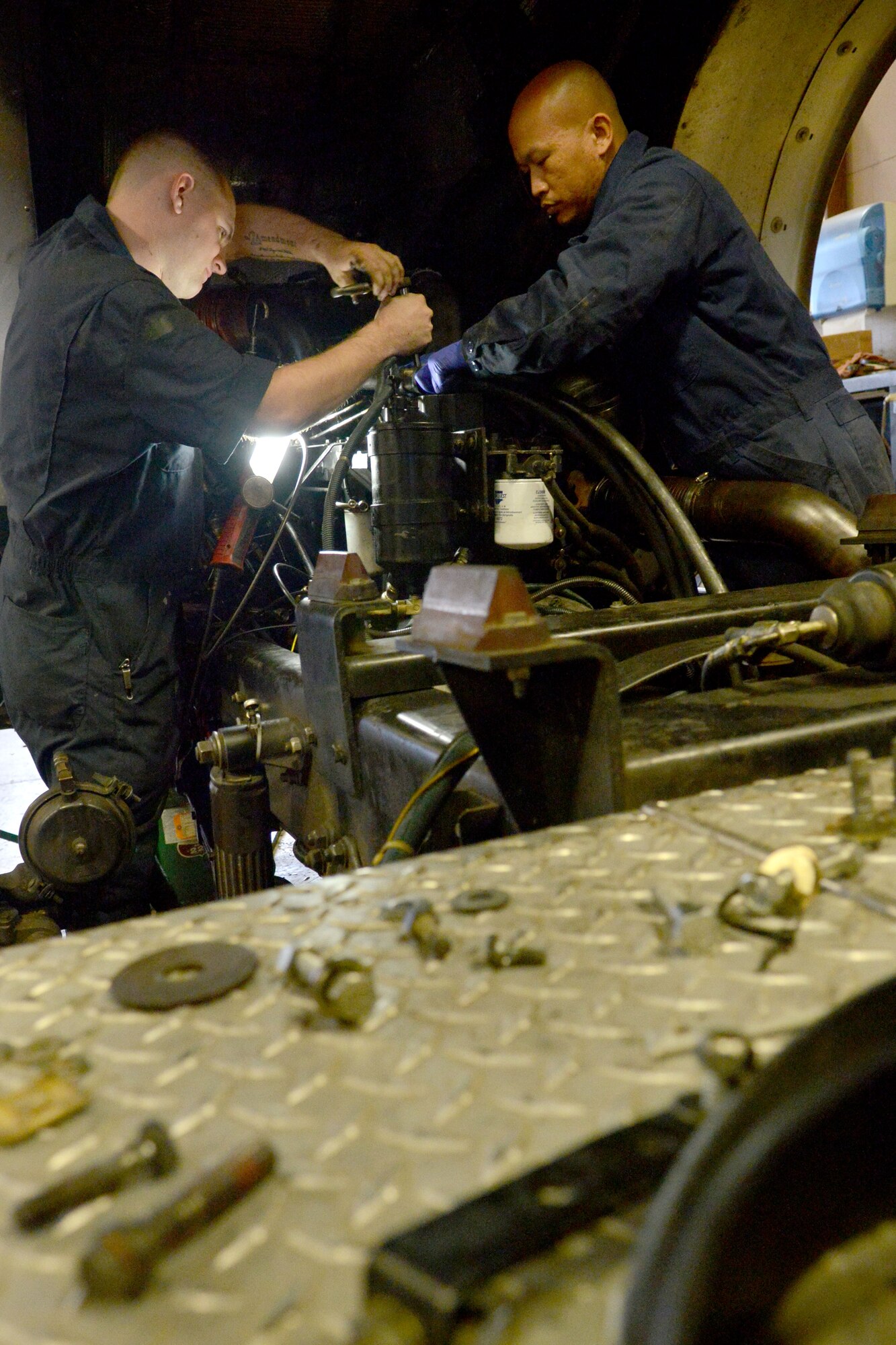 U.S. Air Force Staff Sgt. Vanny Vang and Andrew Sterrett, 20th Logistics Readiness Squadron vehicle and equipment maintainers, assemble a fire truck engine after it is grounded under the hood, Shaw Air Force Base, S.C., Feb. 4, 2014. The maintainers removed a fire truck  engine in order to replace the coolant and had to reinstall the engine into the truck.( U.S. Air Force photo by Senior Airman Ashley L. Gardner/Released)
