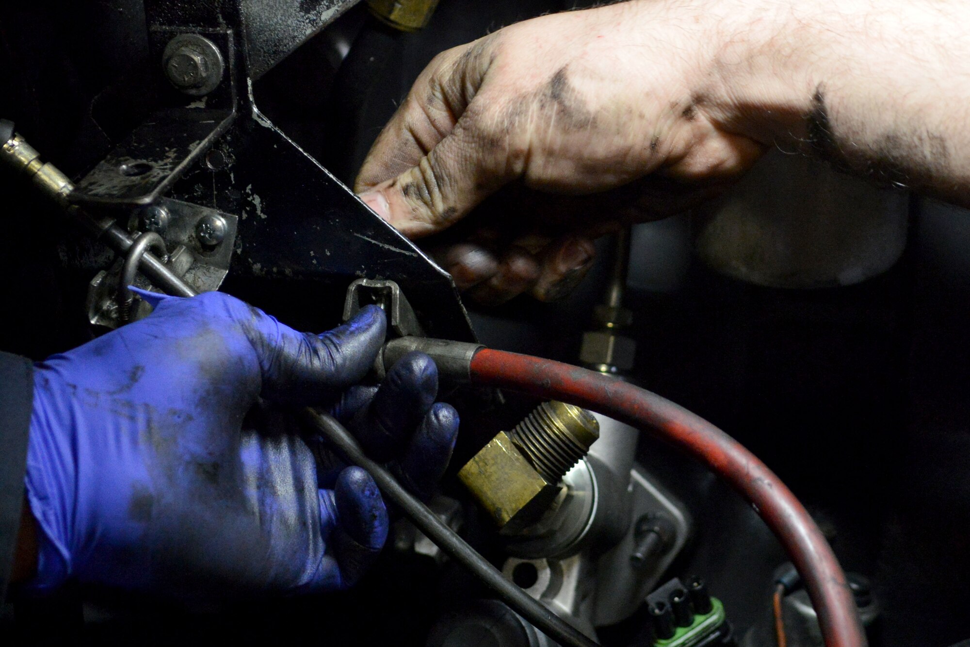 U.S. Air Force Staff Sgt. Vanny Vang and Andrew Sterrett, 20th Logistics Readiness Squadron vehicle and equipment maintainers, hands are shown while connecting key parts to a fire truck engine, Shaw Air Force Base, S.C., Feb. 4, 2014. The maintainers removed a fire truck  engine in order to replace the coolant and had to reinstall the engine into the truck.( U.S. Air Force photo by Senior Airman Ashley L. Gardner/Released)