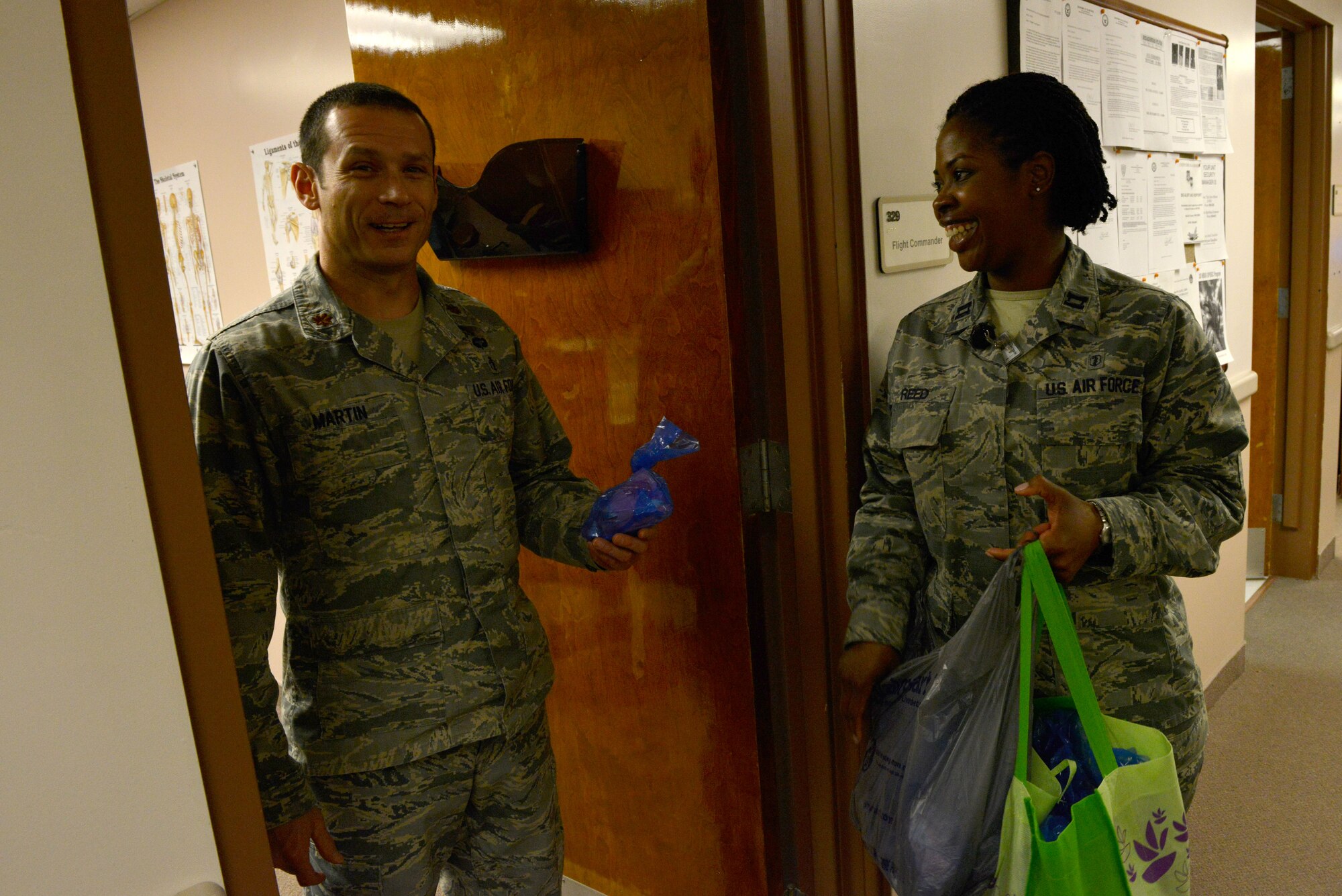 U.S. Air Force Maj. Justin Martin, 20th Medical Operations Squadron physical therapist, holds a bag of candy after reciving it from Capt. Lateasa Reed, 20th Medical Operations Squadron clinical social worker, at Shaw Air Force Base, S.C., Jan. 28, 2014. Reed was passing out bags of candy to Biomedical Sciences Corps officers as well as the technicians and civilians that support them as part of BSC appreciation week. (U.S. Air Force photo by Airman 1st Class Jensen Stidham/Released)