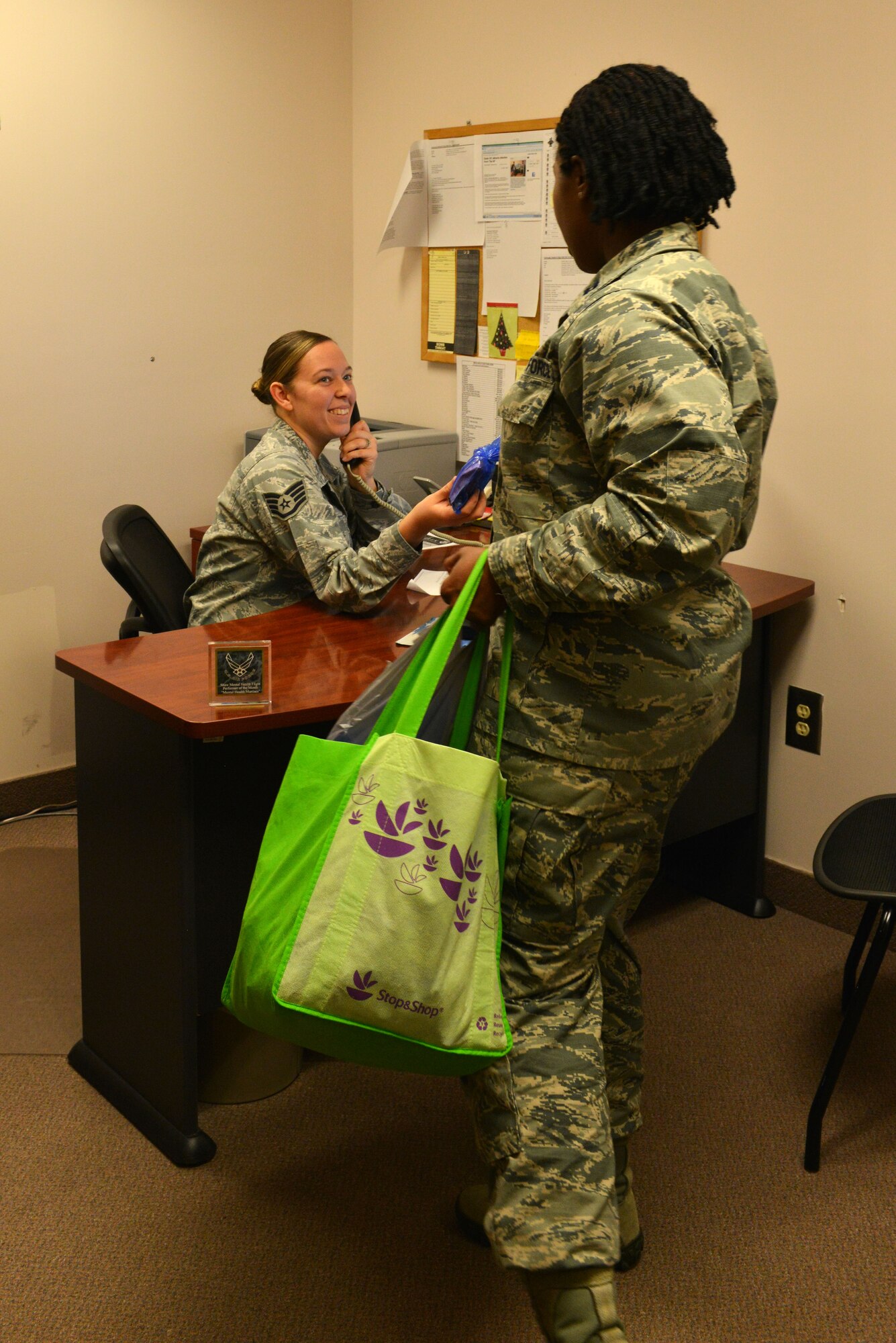 U.S. Air Force Capt. Lateasa Reed, 20th Medical Operations Squadron clinical social worker, hands Staff Sgt. Natalie Yarbrough, 20th MDOS mental health technician, a bag of candy at Shaw Air Force Base, S.C., Jan. 28, 2014. Reed, along with Lt. Col. David Walmsley, 20th Medical Support Squadron commander, was passing out candy to the Biomedical Sciences Corps officers and the technicians and civilians that support them as a celebration of BSC appreciation week. (U.S. Air Force photo by Airman 1st Class Jensen Stidham/Released)