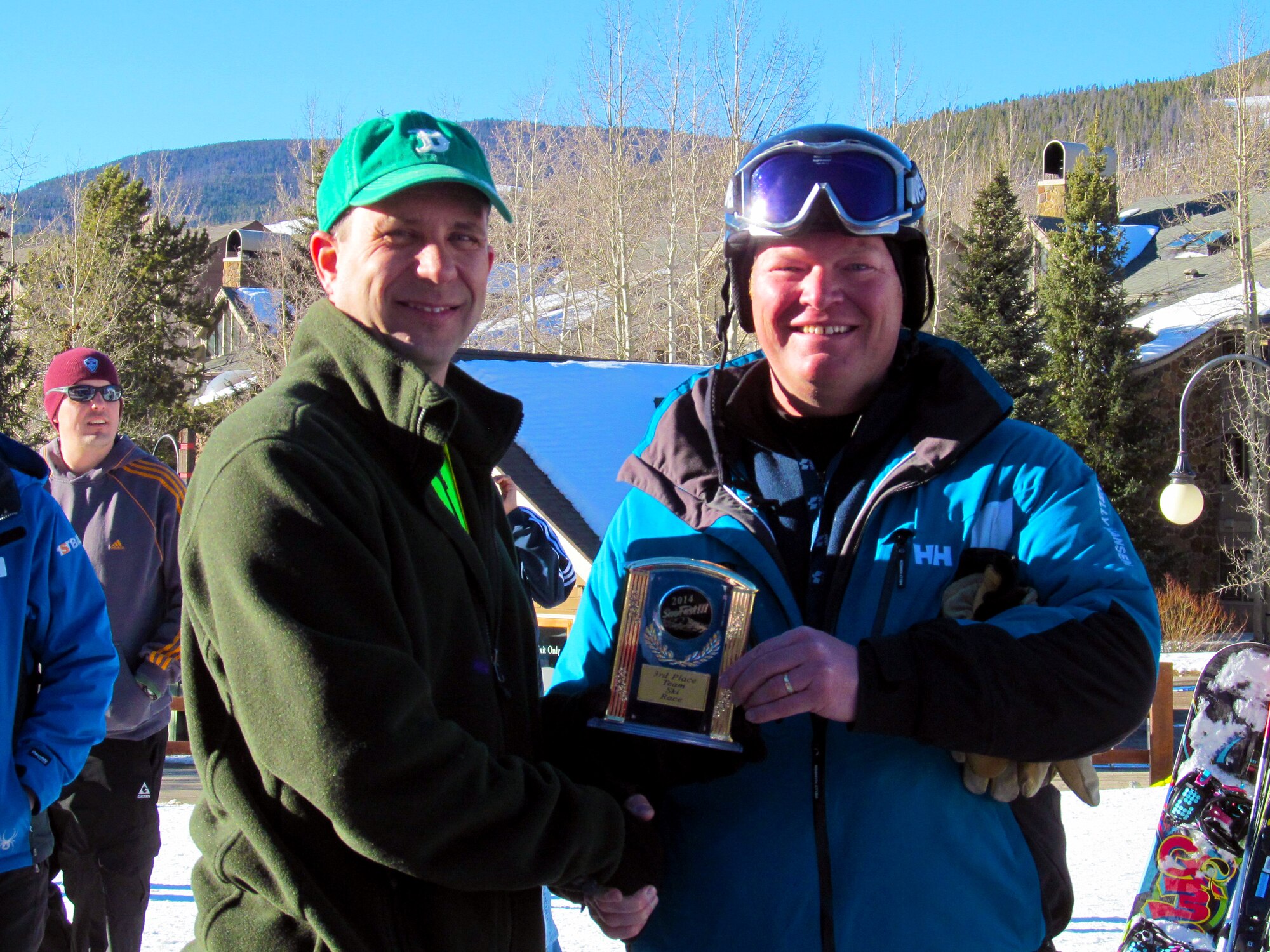 Air Force Col. John E. Shaw presents a trophy to AF Reserve Maj. Aaron T. Haase Jan. 25, 2014, during SnoFest at Keystone, Colo. Haase, a 310th Space Wing Judge Advocate General based at Schriever Air Force Base, Colo., accepted the award on behalf of his four-person team who placed third in a timed ski event. SnoFest is an annual winter event hosted by Colorado Front Range military bases that features skiing, snowboarding, lodging, parties, giveaways, races and non-skiing events for the military community, to include active duty, Department of Defense civilians, family members and retirees. Shaw commands the 21st Space Wing at Peterson AFB, Colo. (Courtesy photo/Hope Haase)