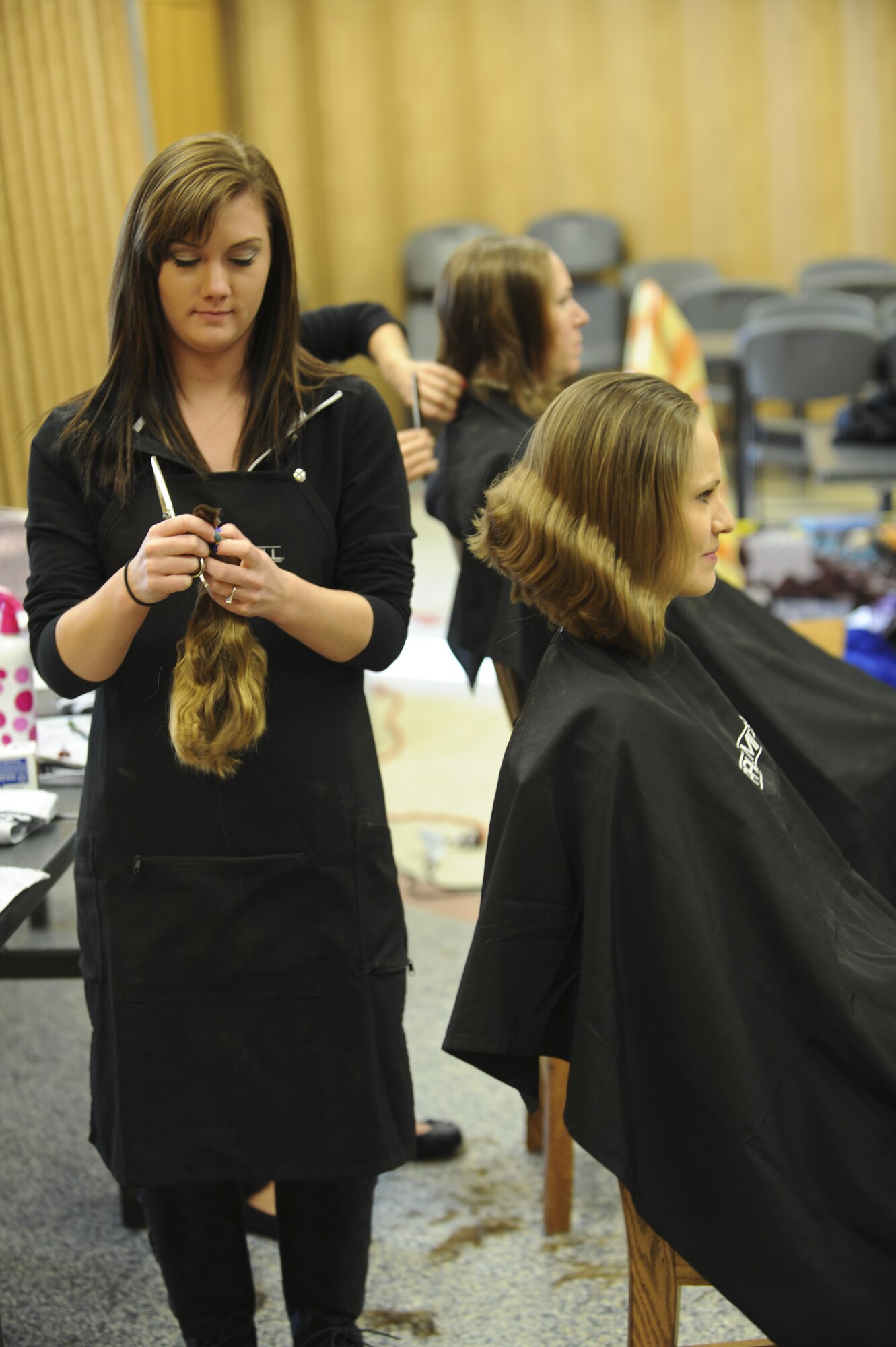 Kelsey Ciesielski from Paul Mitchell the School Colorado Springs gathers more than 10 inches of hair from Staff Sgt. Kendra Mauldin, 50th Space Wing, Jan. 24 at the Peterson Chapel for Locks for Love. The Locks For Love, “Give a Little, Give a Lock,” event gathered more than 19 locks of hair for children with long term hair loss illnesses. (U.S. Air Force photo/Staff Sgt. Jacob Morgan)