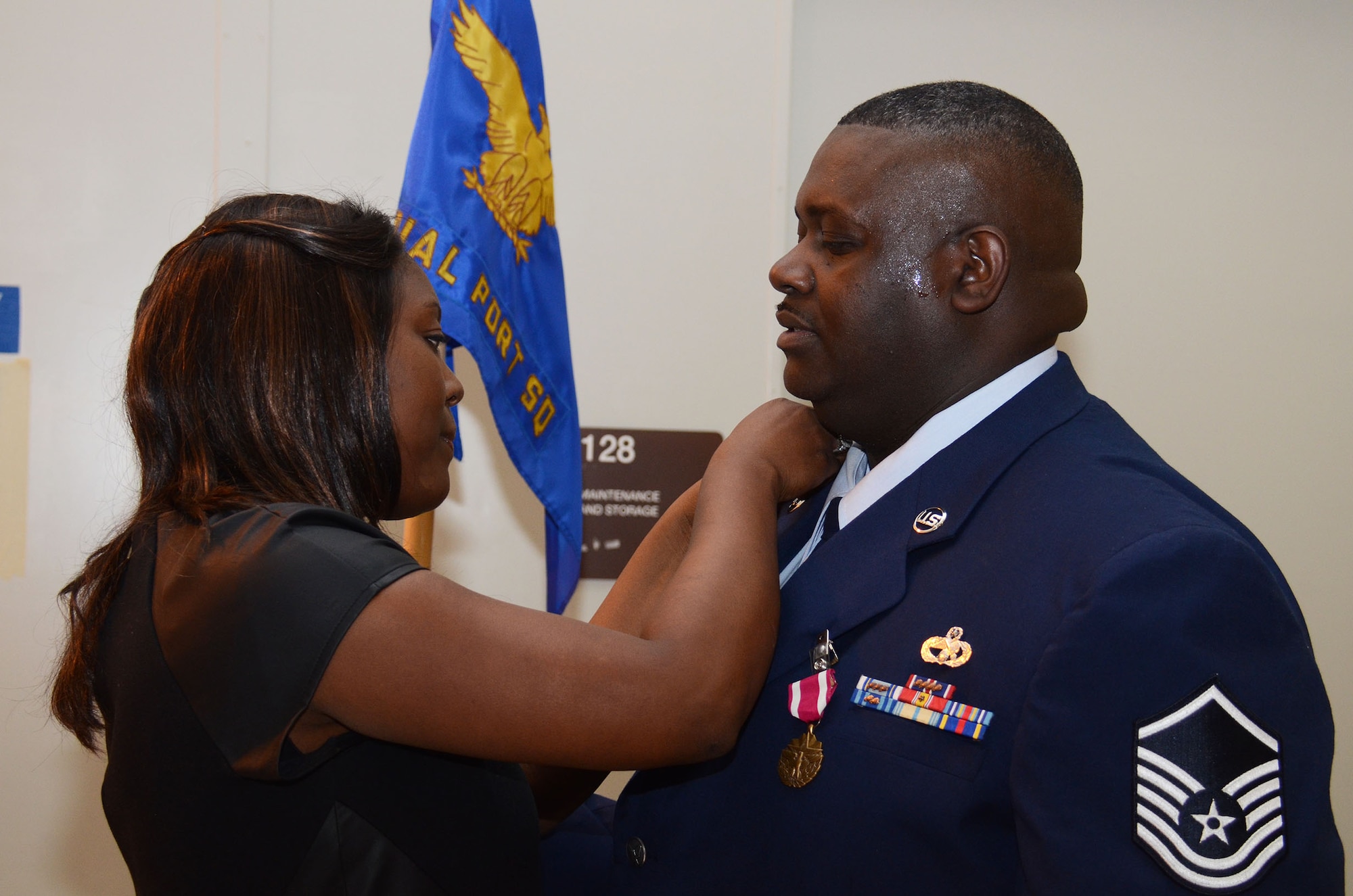 Master Sgt. Darrell Hatcher's wife assists with the pinning of the Meritorious Service Medal during his retirement ceremony at the 80th Aerial Port Squadron Dec. 7, honoring 26 years of military service. (U.S. Air Force photo/Don Peek)
