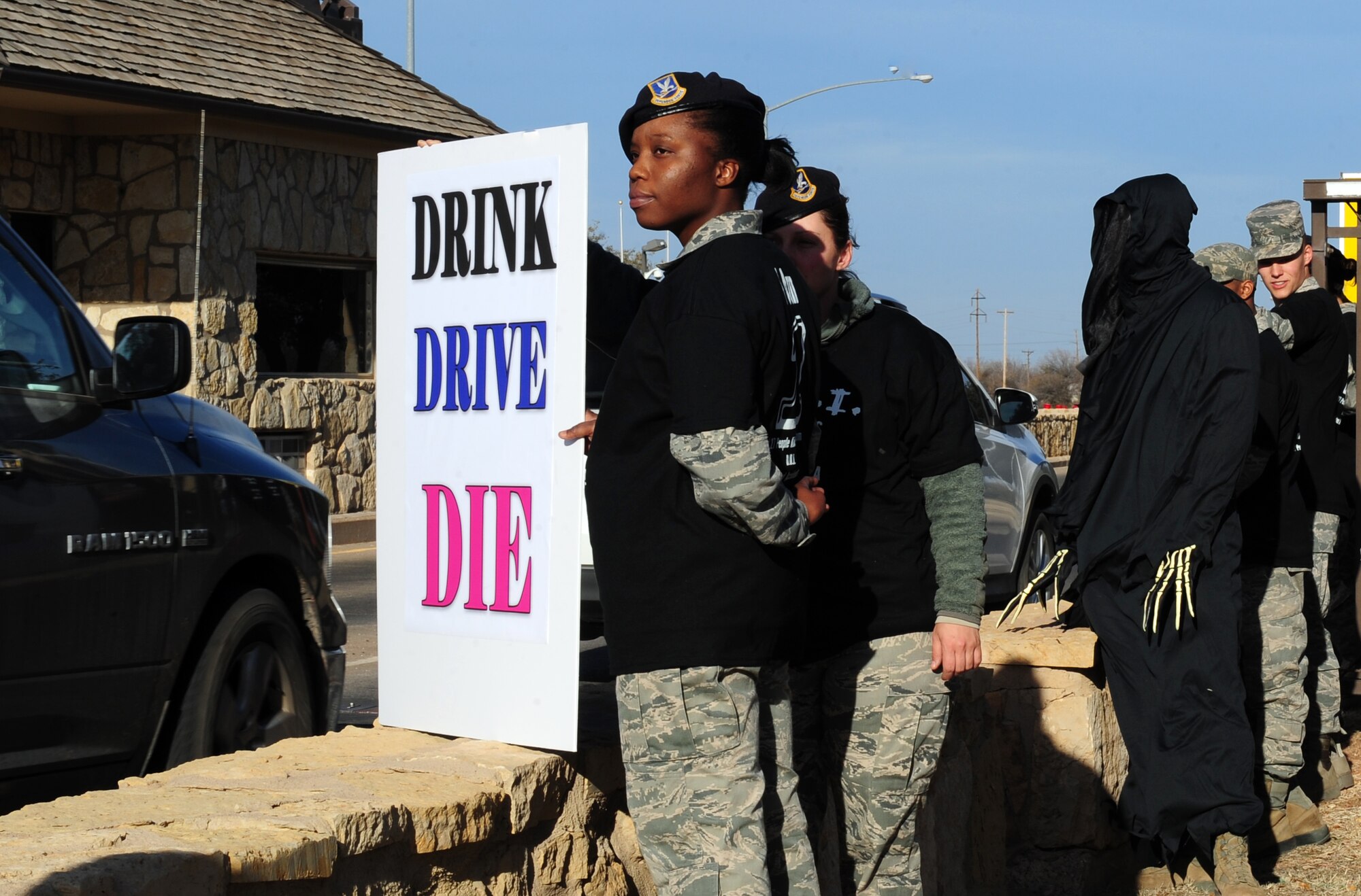 U.S. Air Force Staff Sgt. Cherrell Wade, 7th Security Forces Squadron NCO in charge of installation security, holds a sign near the front gate during a driving under the influence awareness campaign Jan. 30, 2014, at Dyess Air Force Base, Texas. Airmen stood alongside the grim reaper to signify the dangers of drinking and driving. In America, on average, nearly 12,000 people die every year in DUI-related accidents. The purpose of this campaign was to educate Team Dyess on the effects and consequences of driving while intoxicated and DUIs. DWI refers to driving while intoxicated by alcohol, while DUI is used when the driver is charged with being under the influence of alcohol or drugs. (U.S. Air Force photo by Senior Airman Kia Atkins/Released)