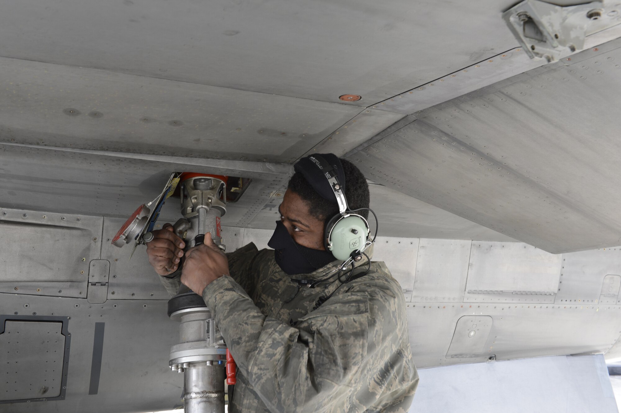 U.S. Air Force Senior Airman Richard Turner, 52nd Aircraft Maintenance Squadron engine technician from Nork, N.J., fastens a type-4 hydrant system to refuel an F-16 Fighting Falcon during a hot-pit refueling at Spangdahlem Air Base, Jan 28, 2014. Hot-pit refueling saves time, manpower and equipment usage by refueling active aircraft between training missions. (U.S. Air Force photo by Staff Sgt. Christopher Ruano/released)