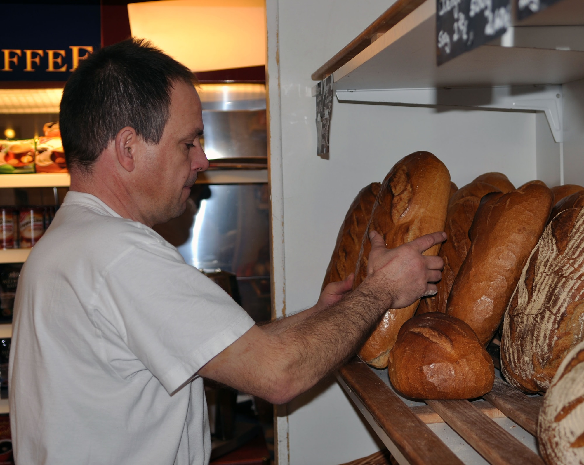 A local baker „Meister“ fills up a shelf with fresh bread from the morning baking. There are about 300 different types of bread produced in Germany. The most common and less expensive bread is known as Roggenmischbrot. It is rye mixed bread with wheat or other flour. Bauernbrot is similar to Roggenmischbrot but a bit tastier. It is usually round. Weizenmischbrot is also similar to Roggenmischbrot, it is also light in color, but is made with different proportions of wheat and rye. The shapes of breads are only limited by the bakers’ imagination. Bread rolls are very popular in Germany. (U.S. Air Force photo by Iris Reiff/Released)
