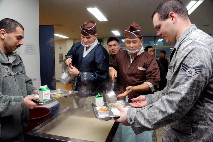 Col. S. Clinton Hinote, 8th Fighter Wing commander, and Col. Song Ho Jung, Republic of Korea air force 38th Fighter Group commander, serve members of the 38th Fighter Group and the 8th Fighter Wing breakfast as part of the Lunar New Year celebration at Kunsan Air Base, Republic of Korea, Feb. 1, 2014. ‘Breakfast’ consisted of Ttok Guk, which is soup prepared with rice cakes, scalded zucchini, and kimchi. U.S. and RoKaf Airmen came together to celebrate the new year by participating in a traditional bowing ceremony, eating Korean cuisine and playing a variety of games. (U.S. Air Force photo by Staff Sgt. Jessica Haas/Released)