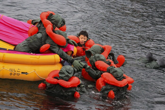 Japan Maritime Self-Defense Force aviators assist each other in boarding an inflatable raft during their mandatory, semi-annual Life-Saving Survival Training aboard Marine Corps Air Station Iwakuni, Japan, Jan. 28, 2014. All participants embarked the raft before receiving the order from their instructor to make the final swim to shore.

