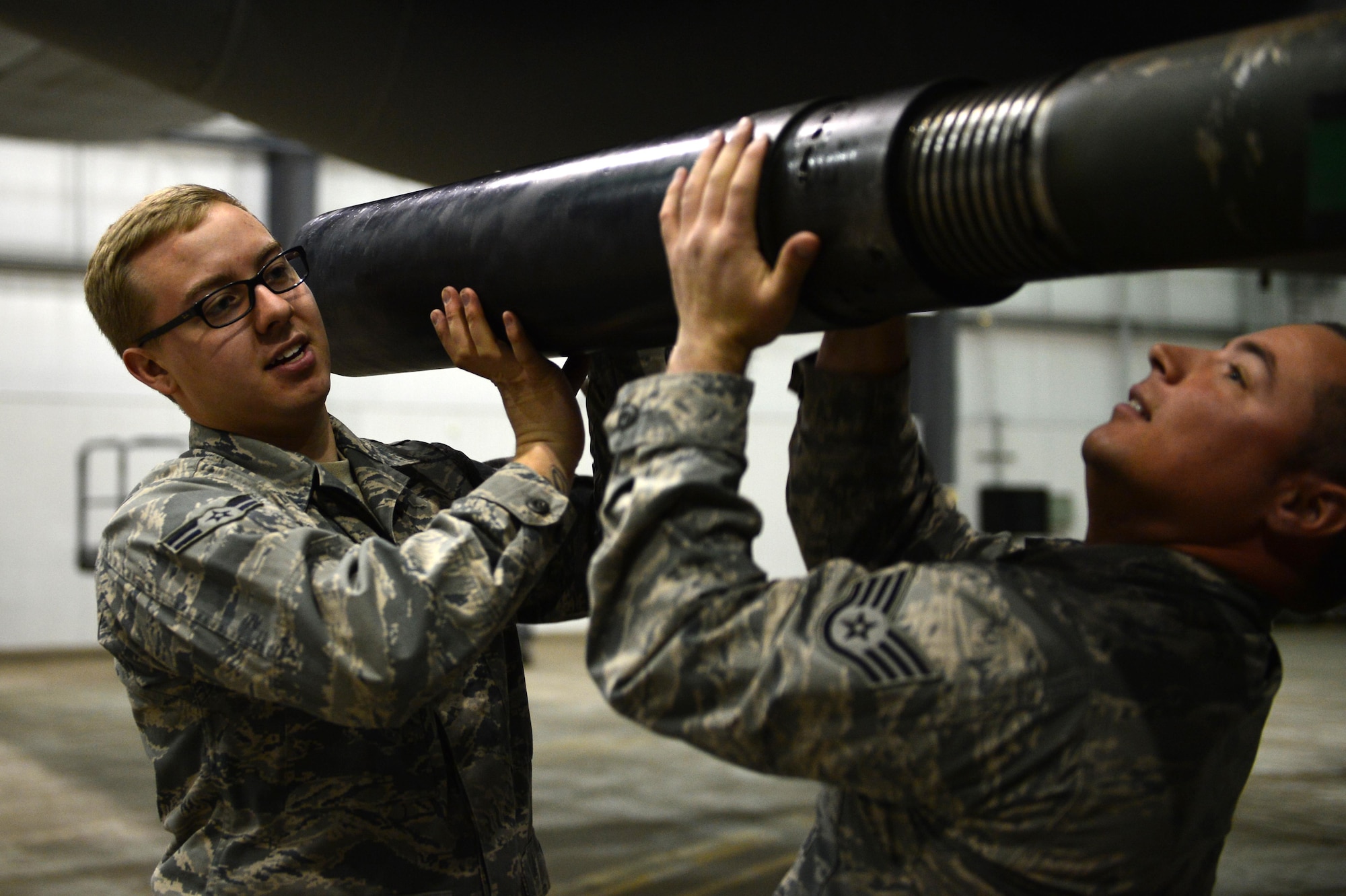 U.S. Air Force Staff Sgt. Seth Rosbrugh, 27th Special Operations Maintenance Squadron armament technician Airman 1st Class Thomas Orton-McIntyre, 27 SOMXS armament technician, remove a 105 mm blast diffuser from the AC-130H Spectre. While juggling real-world mission requirements, maintainers dedicated additional hours each day to ensure the necessary tasks of demilitarization were completed. (U.S. Air Force photo/ Airman 1st Class Eboni Reece)
 