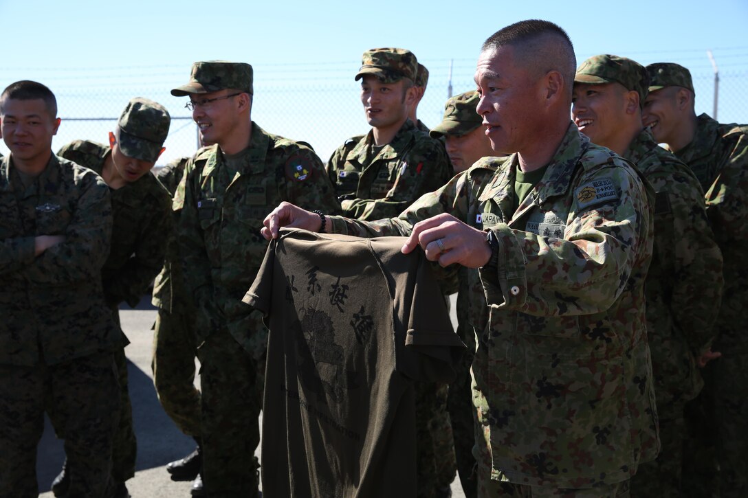 A soldier from the Japan Ground Self-Defense Force shows a gift to U.S. Marines with 1st Air Naval Gunfire Liaison Company during Exercise Iron Fist 2014 aboard Camp Pendleton, Calif., Feb. 3, 2014. Iron Fist 2014 is an amphibious exercise that brings together Marines and sailors from the 15th Marine Expeditionary Unit, other I Marine Expeditionary Force units, and soldiers from the JGSDF, to promote military interoperability and hone individual and small-unit skills through challenging, complex and realistic training. (U.S. Marine Corps photo by Lance Cpl. Anna K. Albrecht/Released)