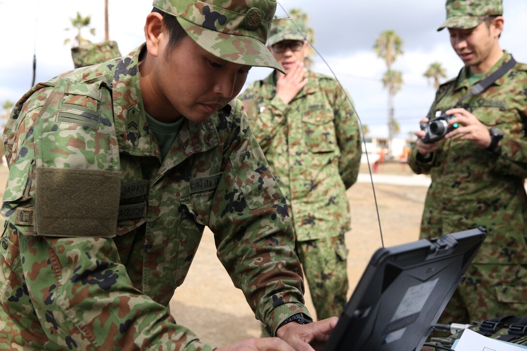 A soldier with the Japan Ground Self-Defense Force and U.S. Marines with the 15th Marine Expeditionary Unit set up radios during Exercise Iron Fist 2014 aboard Camp Pendleton, Calif., Feb. 4, 2014. Iron Fist 2014 is an amphibious exercise that brings together Marines and sailors from the 15th MEU, other I Marine Expeditionary Force units, and soldiers from the JGSDF, to promote military interoperability and hone individual and small-unit skills through challenging, complex and realistic training. (U.S. Marine Corps photo by Lance Cpl. Anna K. Albrecht/Released)