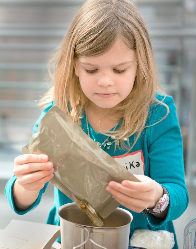 Annika Pugh, daughter of Marine Capt. Doug Pugh, squeezes the contents of a prepackaged ration to prepare a dish at the National Museum of the Marine Corps Second Annual MRE Cook-off in Triangle, Va., Feb. 1, 2014. Annika participated in the contest with her dad and her sister Zoe. (U.S. Marine Corps photo by Cpl. Melissa Karnath)