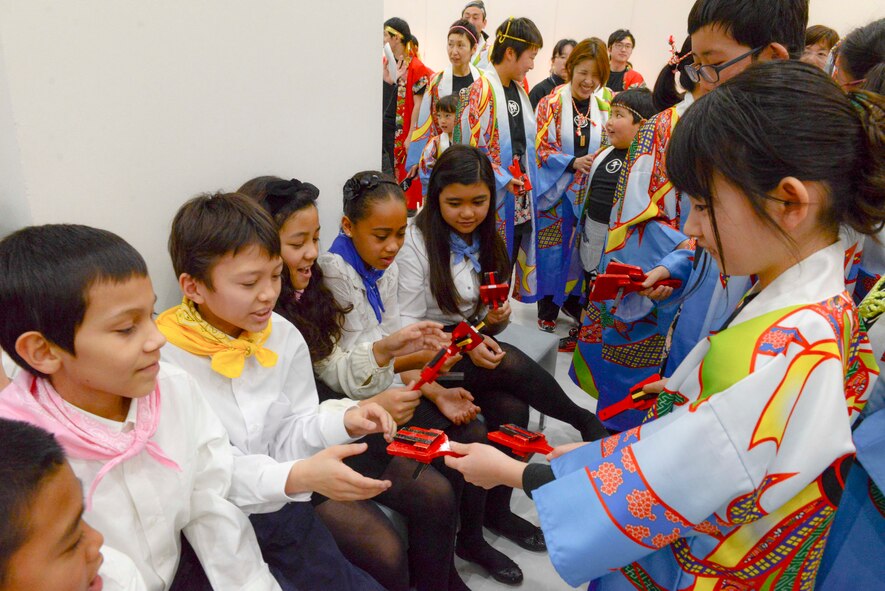 A Japanese child gives a Japanese musical instrument as a gift to a student from Joan K. Mendel elementary school at Tachikawa City, Japan, Feb. 2, 2014.  The children performed at the Japan - U.S. Joint Concert.  (U.S. Air Forces photo by Airman 1st Class Soo C. Kim / released)