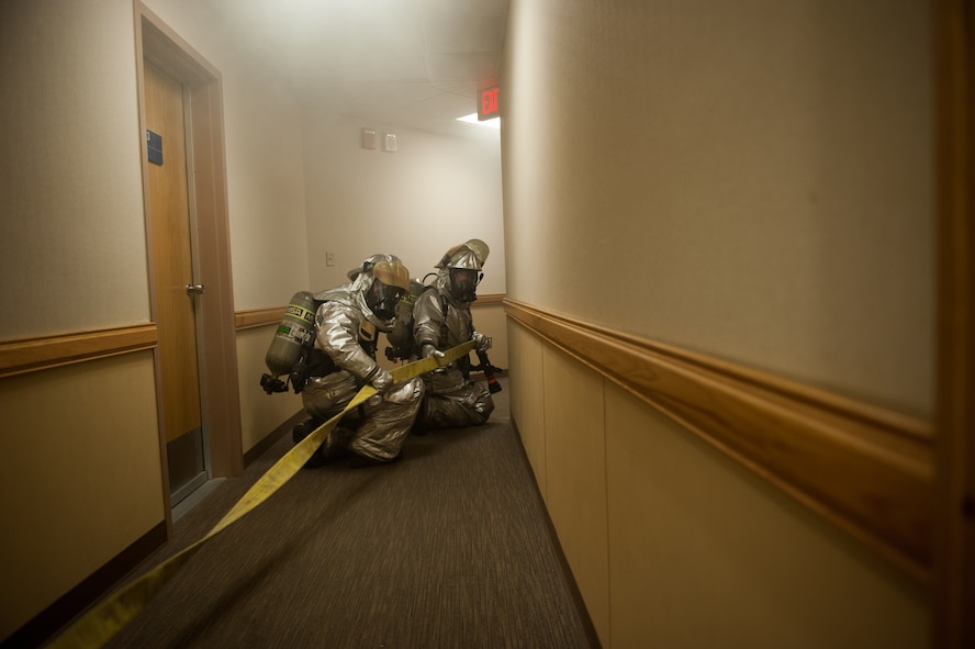 Staff Sgt. Jonathan Fackler, and SrA Stephen Heath, 8th Civil Engineer Squadron firefighters, advance into a simulated burning building during exercise Beverly Midnight 14-01 at Kunsan Air Base, Republic of Korea, Feb. 5, 2014. The fire department searched for the injured and escorted or carried them to medical personnel for treatment. (U.S. Air Force photo by Staff Sgt. Clayton Lenhardt/Released)