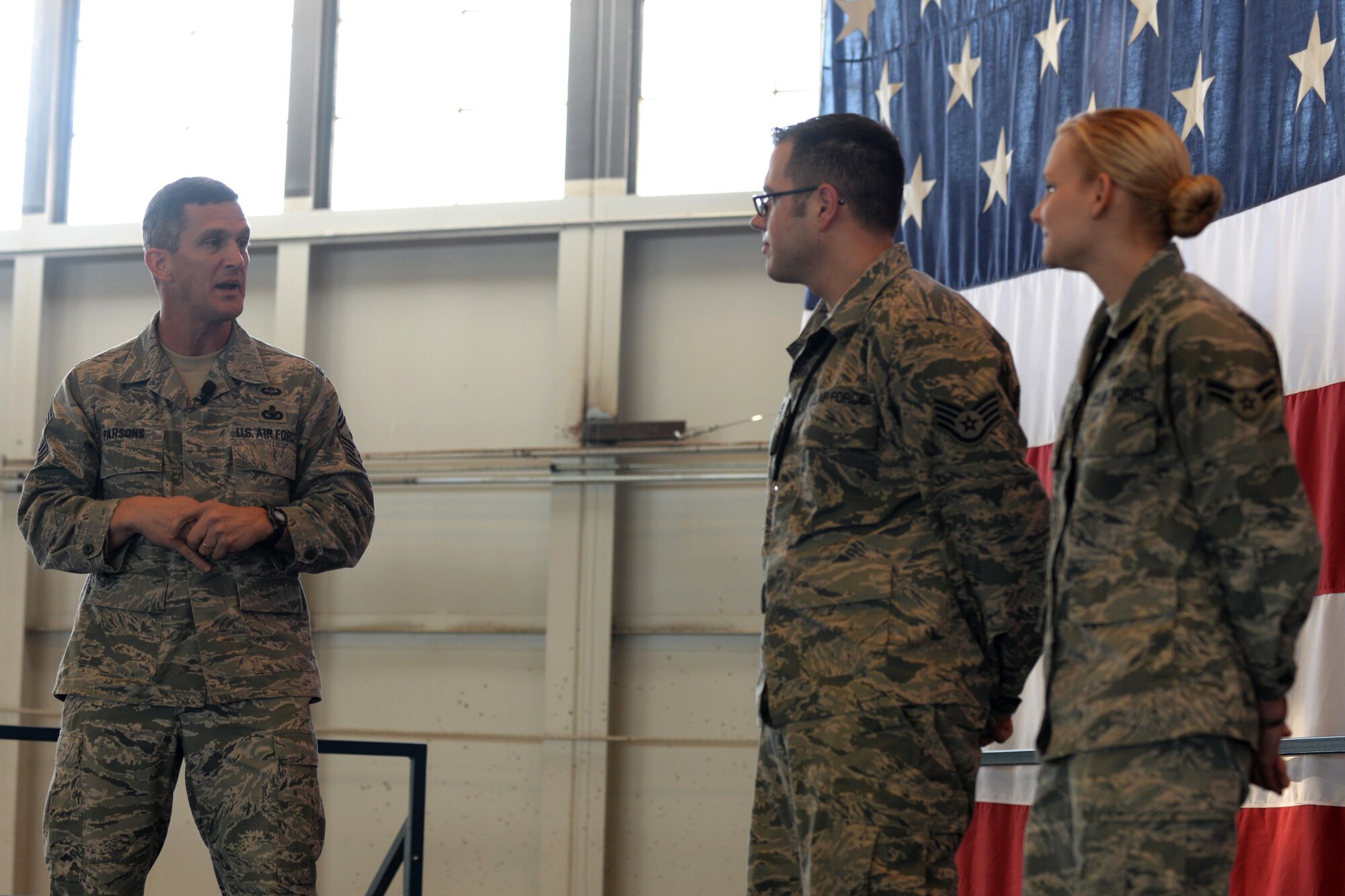 Chief Master Sgt. Richard Parsons, Air Combat Command command chief, recognizes Staff Sgt. David Keeler, 28th Munitions Squadron munitions handling crew chief, and Airman 1st Class Darci Brown, 28th Comptroller Squadron financial analyst, during an enlisted all call in the Pride Hangar at Ellsworth Air Force Base, S.D. Jan. 29, 2014. Parsons coined Keeler and Brown for being superior performers and leading by example. (U.S. Air Force photo by Airman 1st Class, Rebecca Imwalle/Released)