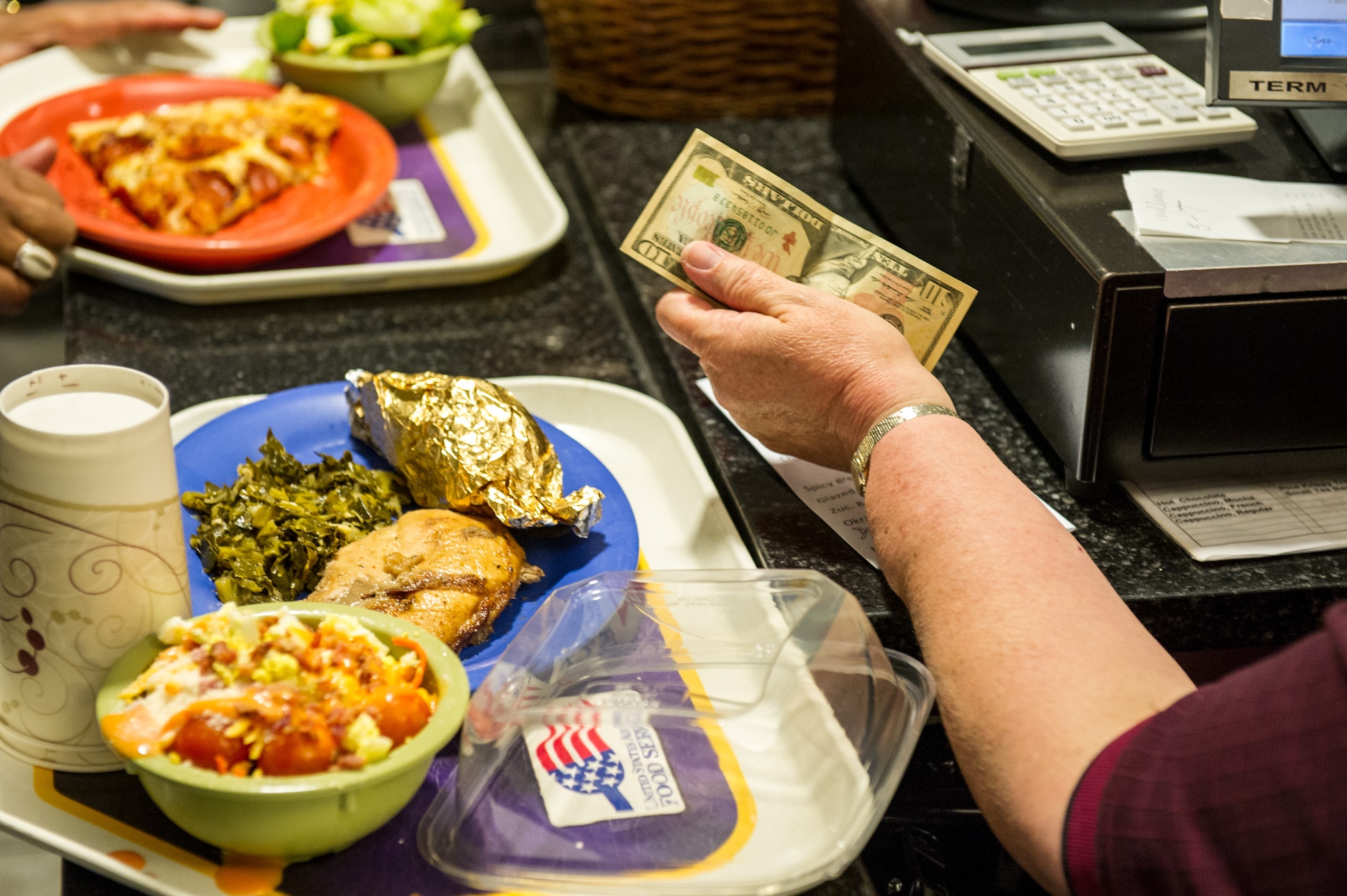 A cashier makes change for a customer during her shift at the Patrick Air Force Base Riverside Dining Facility Feb. 4, 2014. While several menu upgrades have been made, a price increase has is also slated to take place based on customer’s needs. The price increase is attributed to the rise in cost of meat, dairy and produce and the re-validation of more than 1,200 existing recipes. (U.S. Air Force photo/Cory Long)