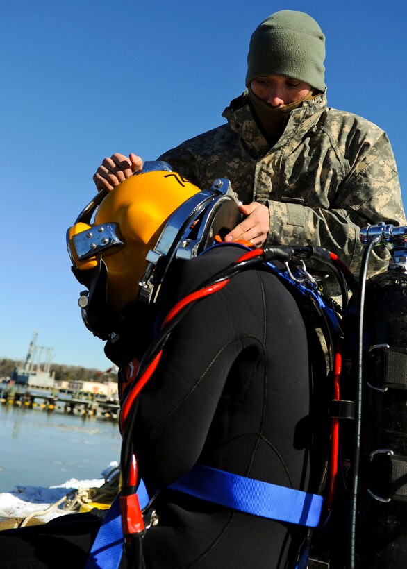 U.S. Army Spc. Royce Clark, 20th Engineer Brigade, 30th Eng. Battalion, 74th Eng. Detachment dive tender, helps 1st Lt. Andrew Kalna, 74th Eng. Det. diver, don his gear during a pier repair mission at Fort Eustis, Va., Jan. 30, 2014. Divers have access to hydraulic tools, underwater welding kits and other specialized equipment to complete their unique missions. (U.S. Air Force photo by Airman 1st Class Austin Harvill/Released)