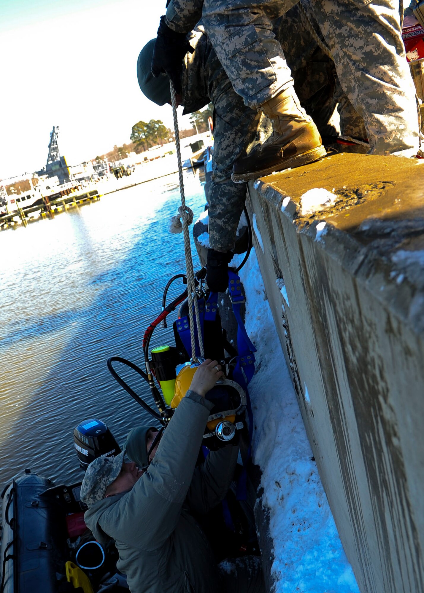Soldiers from the 20th Engineer Brigade, 30th Eng. Battalion, 74th Eng. Detachment transport an air tank and a Kirby Morgan diving helmet onto the dive craft during a pier repair mission at Fort Eustis, Va., Jan. 30, 2014.  Dive teams perform salvage, construction, geospatial intelligence gathering, mobility and counter-mobility missions across the globe.  (U.S. Air Force photo by Airman 1st Class Austin Harvill/Released)