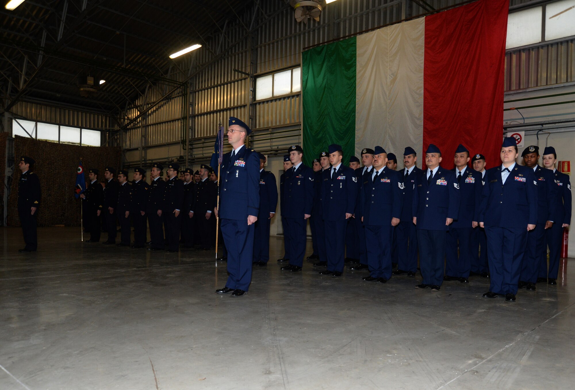 U.S. Air Force Airmen assigned to 704th Munitions Support Squadron and Italian Air Force Airmen assigned to 6th STORMO stand in formation during a ceremony in a hangar at Ghedi Air Base, Italy, Jan. 31, 2014. The ceremony marked the 50th anniversary of the partnership between both air forces at Ghedi Air Base. (U.S. Air Force photo by Staff Sgt. Joe W. McFadden / Released)