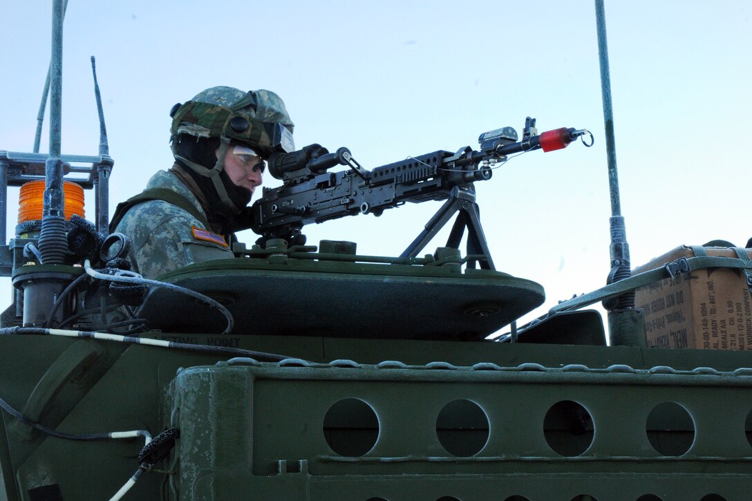 A soldier peers through the scope of an M240 machine gun during a training mission on Forward Operating Base Sparta on Joint Base Elmendorf-Richardson, Alaska, Jan. 30, 2014.