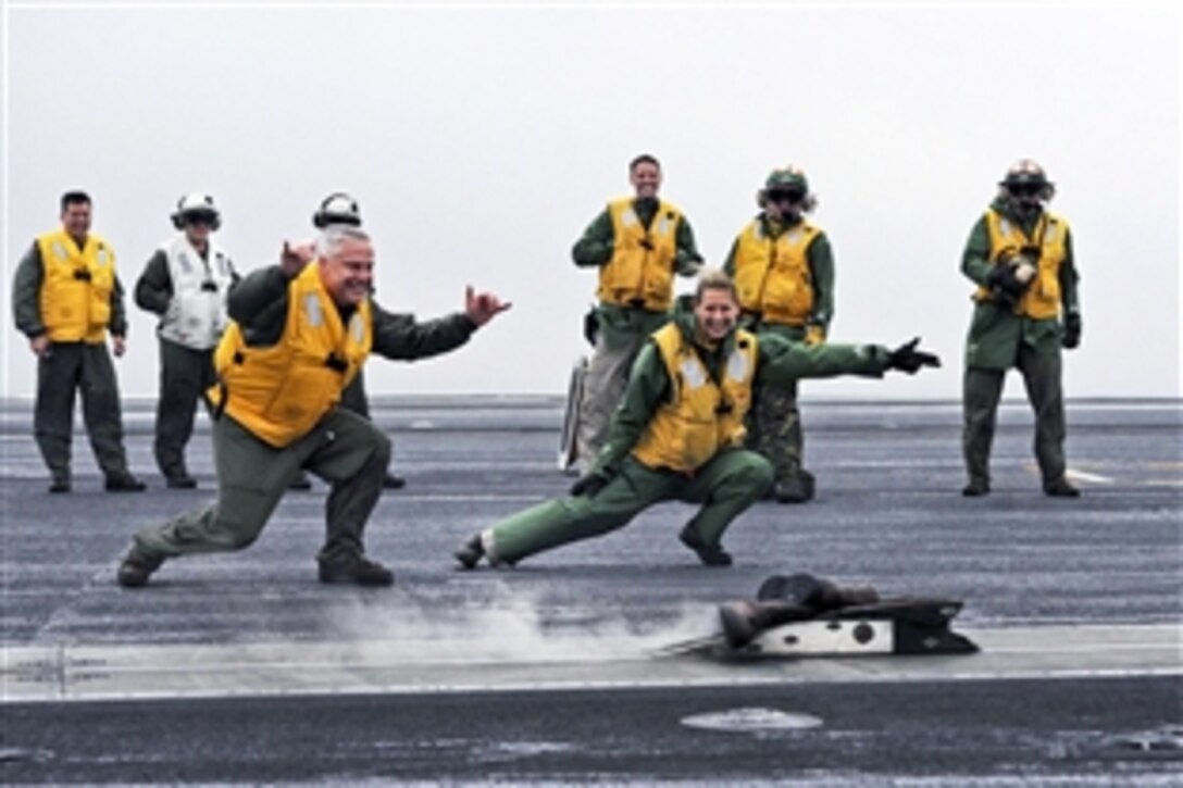 U.S. Navy Cmdr. Daniel Case, left, and Lt. Kari Szewezyk signal for Case’s boots to be launched off the flight deck of the USS Theodore Roosevelt in the Atlantic Ocean, Feb. 3, 2014. It is a tradition for aviators to launch their boots from the catapult of an aircraft carrier when they transfer from the ship. The Roosevelt is training to prepare for future deployments.