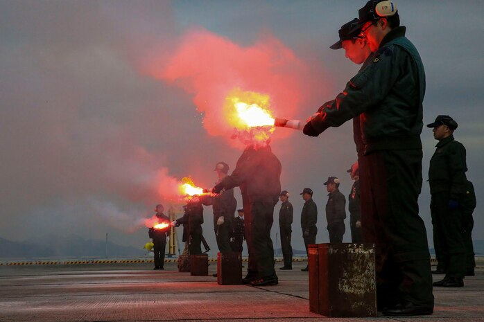 Japan Maritime Self-Defense Force aviators light night-time smoke signals as part of their mandatory, semi-annual Life-Saving Survival Training aboard Marine Corps Air Station Iwakuni, Japan, Jan. 28, 2014. Night-time smoke signals use grey smoke with a flashing red light, while day-time smoke signals are bright red in color. The signals burn for approximately 70 seconds. 